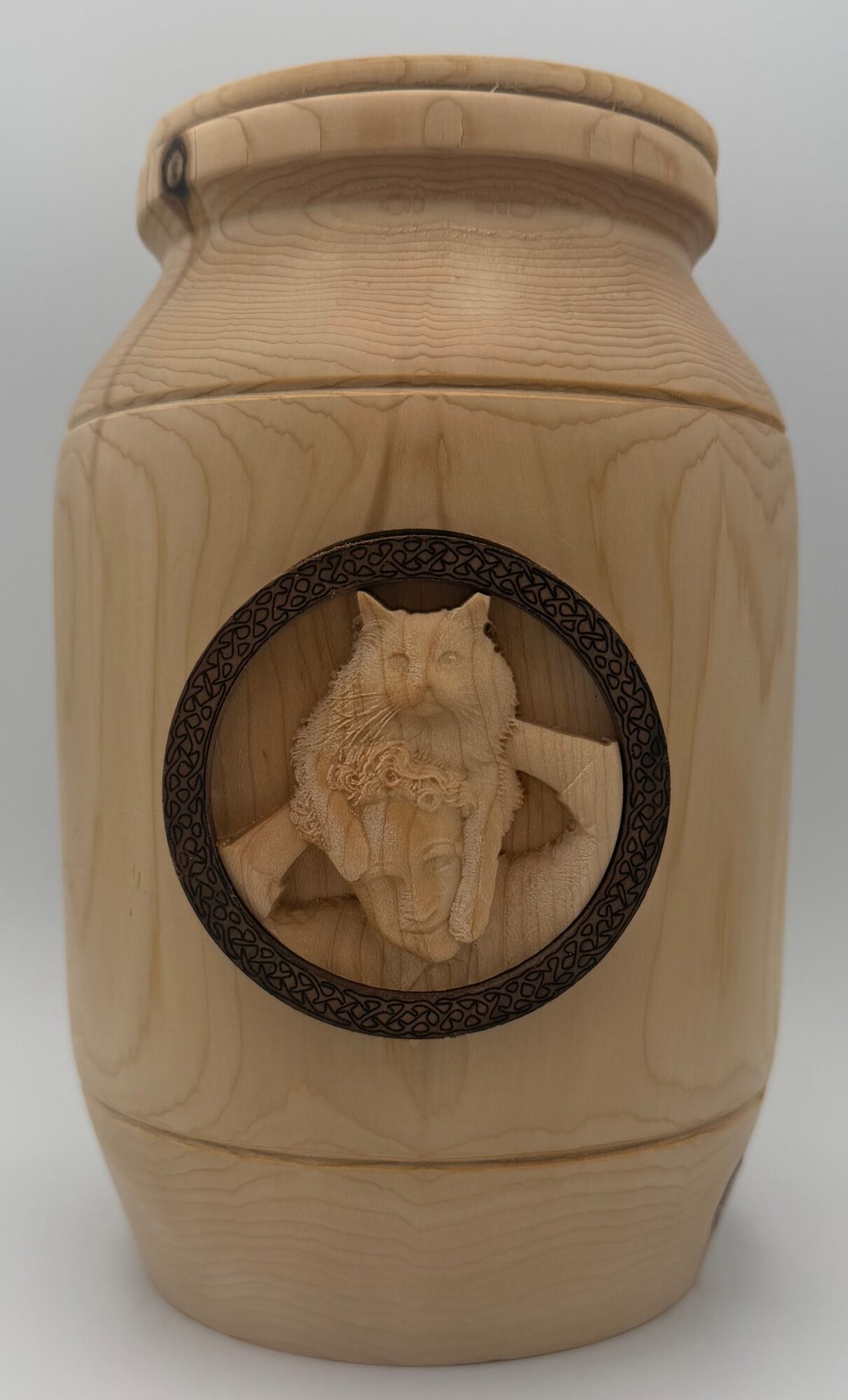 Wooden container with a circular opening containing a carved figure inside, against a plain background.
