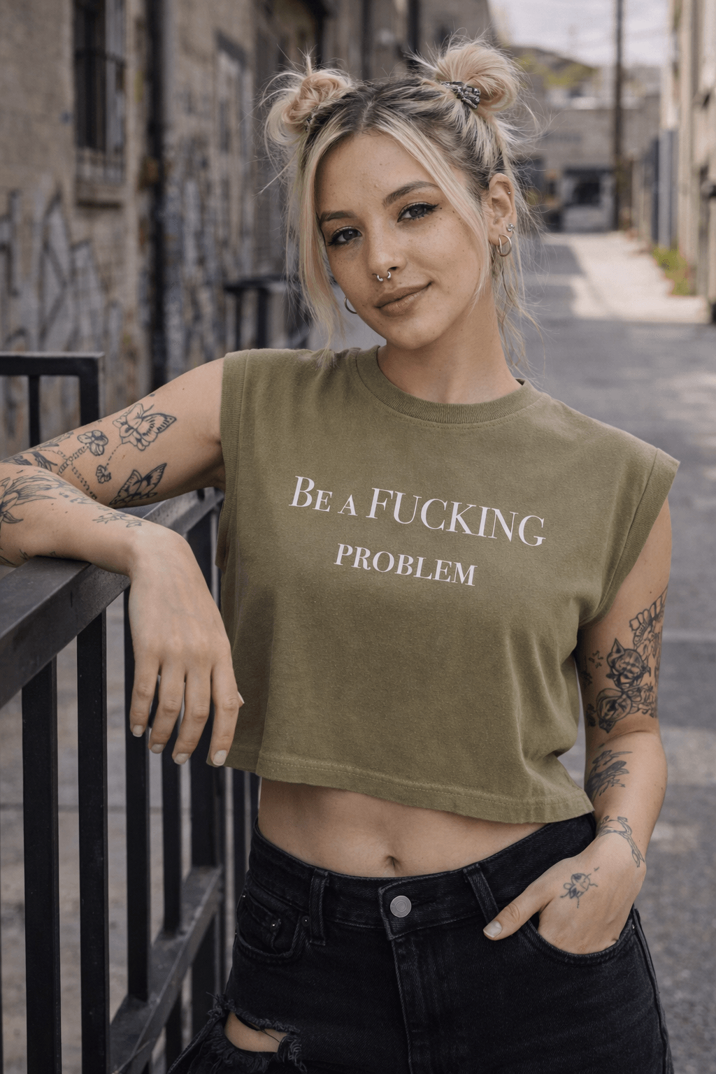 Young woman with blonde hair styled in buns, wearing a green sleeveless crop top with text, standing outdoors in an alleyway.