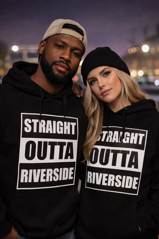 Two people wearing matching hoodies with text, standing outdoors at night with blurred lights in background.