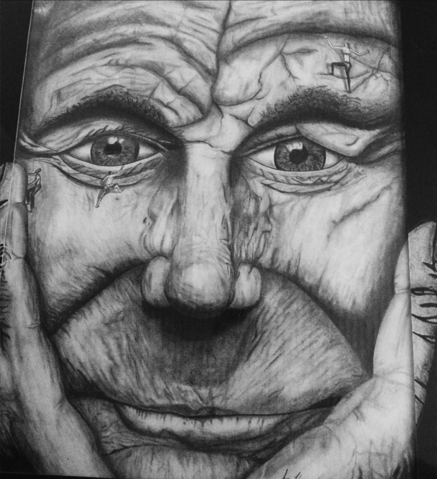 Close-up of a detailed, realistic drawing of an elderly person's face with hands on cheeks, smiling gently.