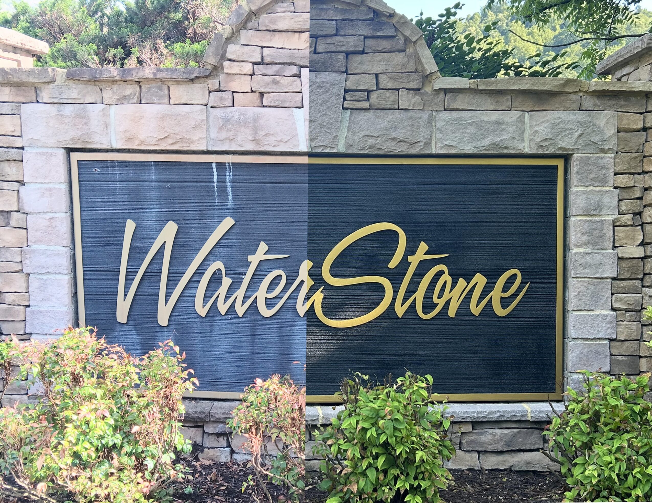 Sign with the words WaterStone in gold cursive font on a dark background, surrounded by stone and greenery.