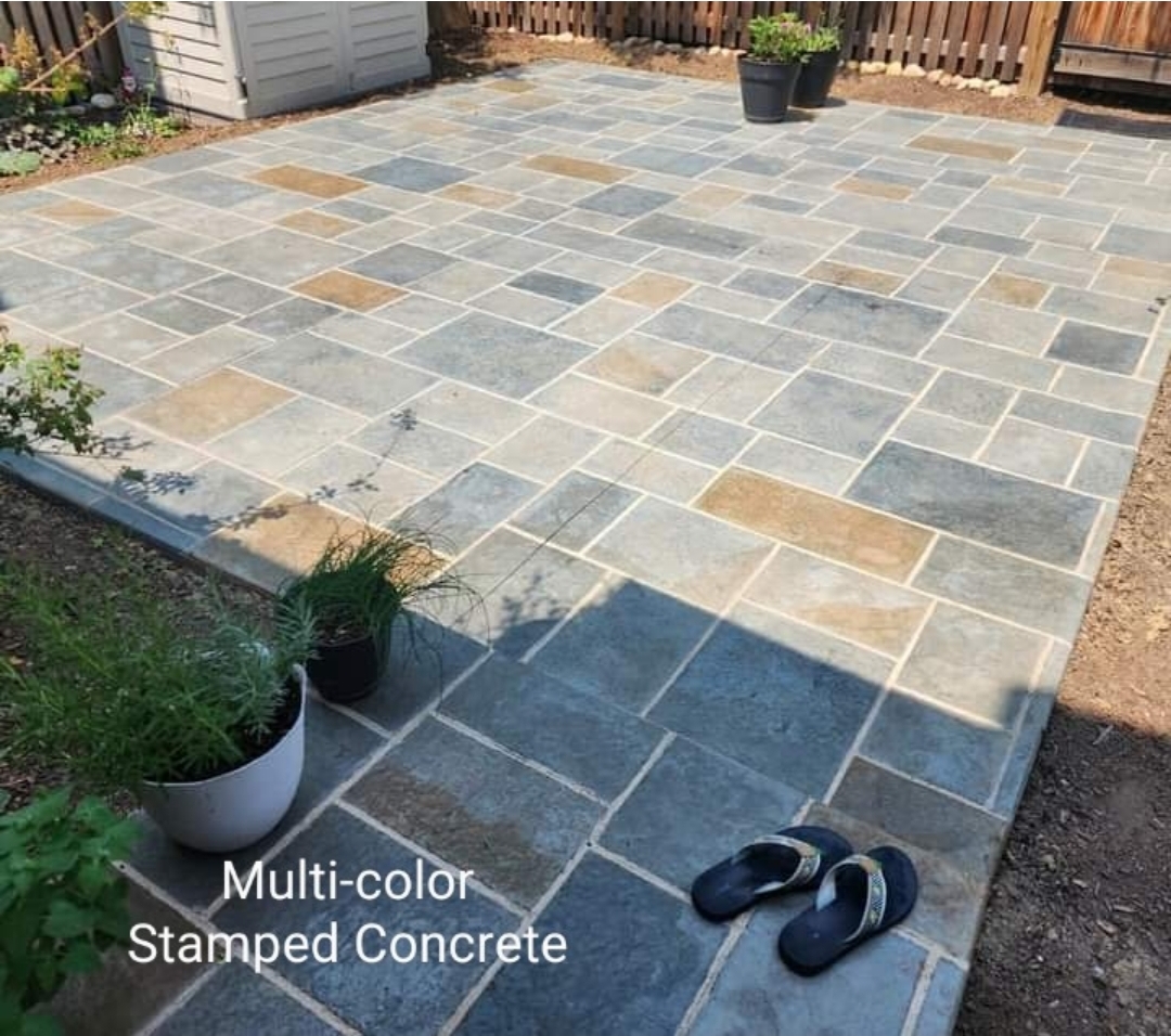Patio with multicolored stamped concrete tiles, potted plants, and a pair of slippers on the ground.