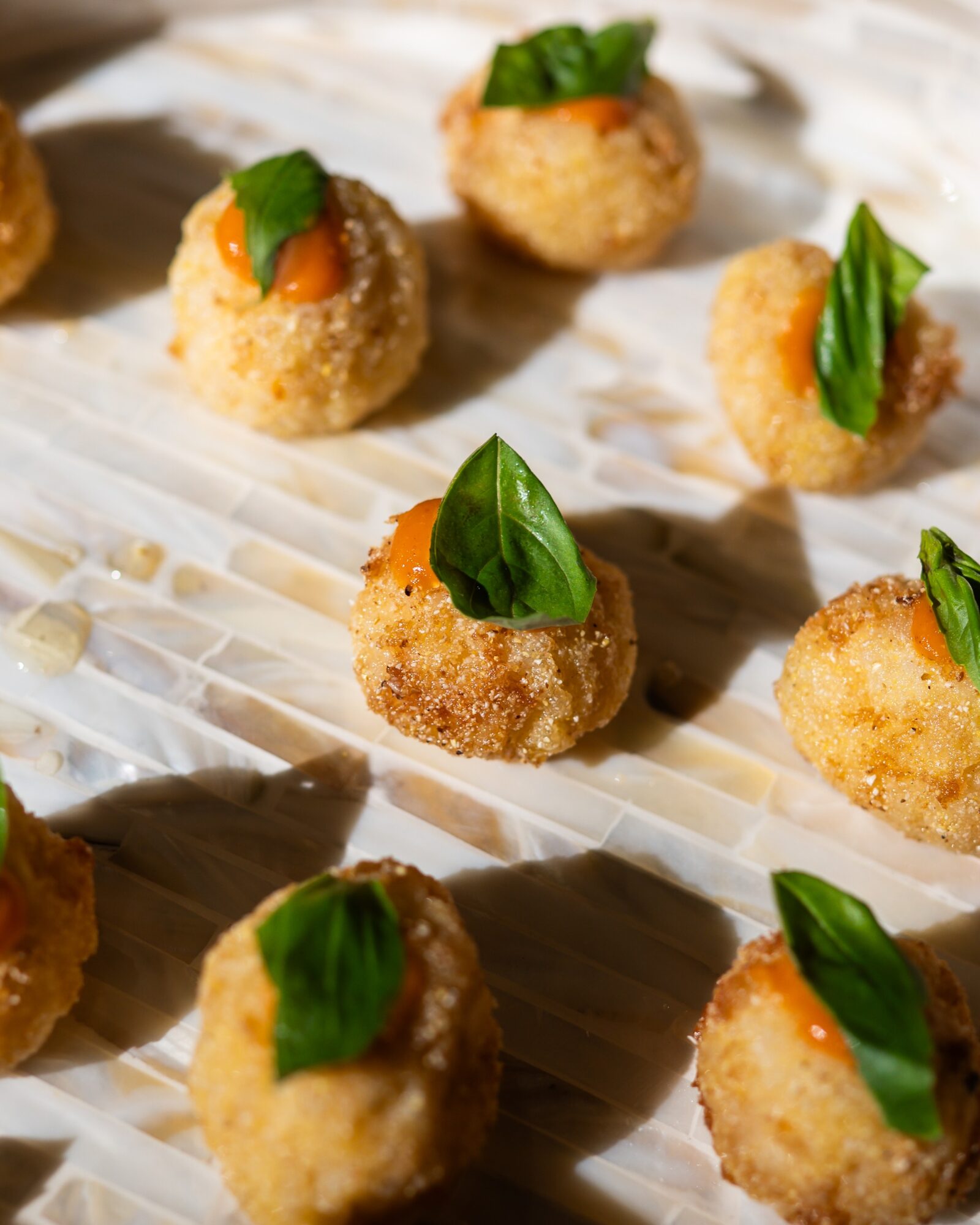 Fried appetizers topped with green herbs on a white paper-lined surface.