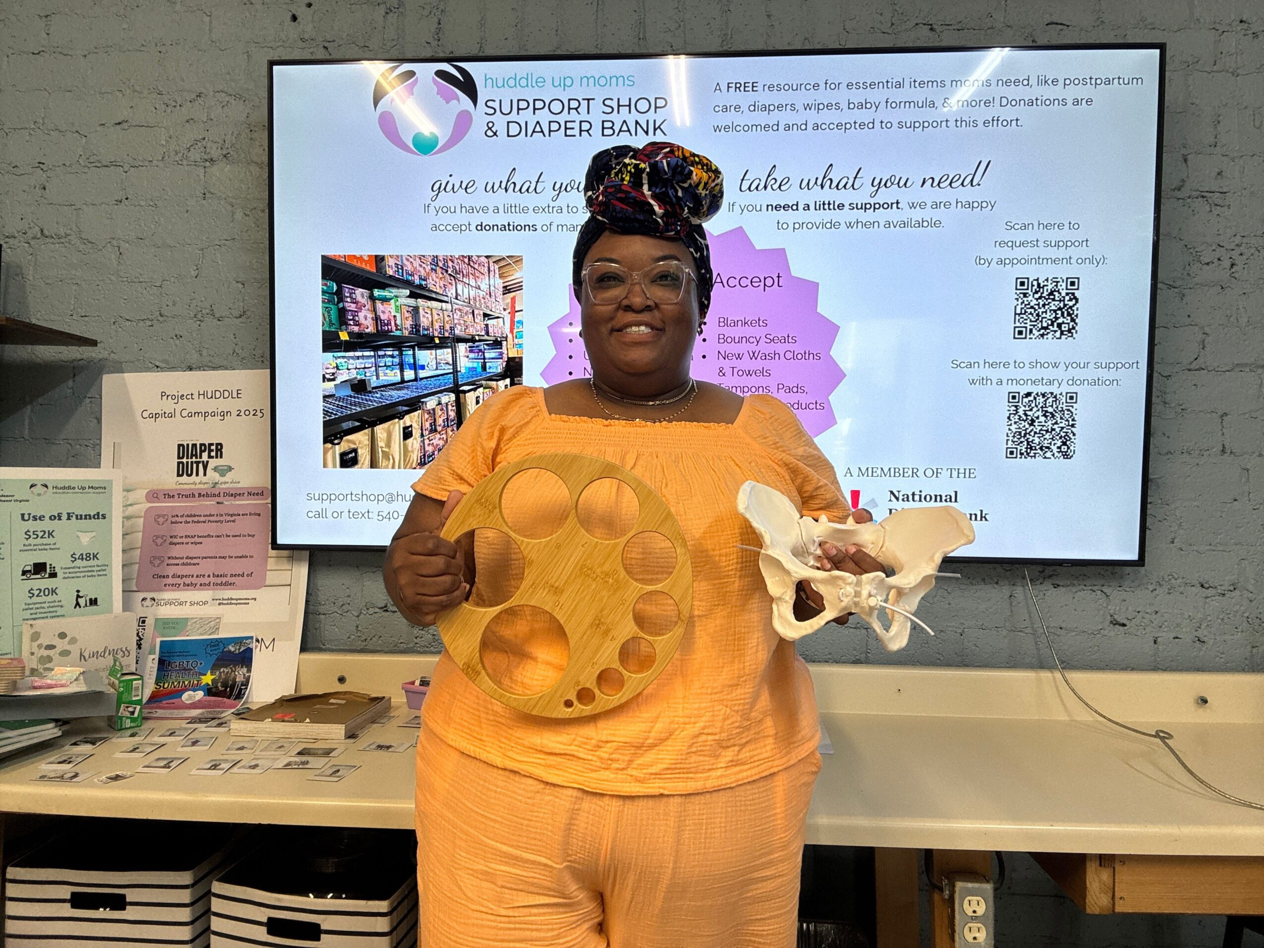 Person in orange shirt and glasses standing in front of a large screen displaying text and images, upside down.
