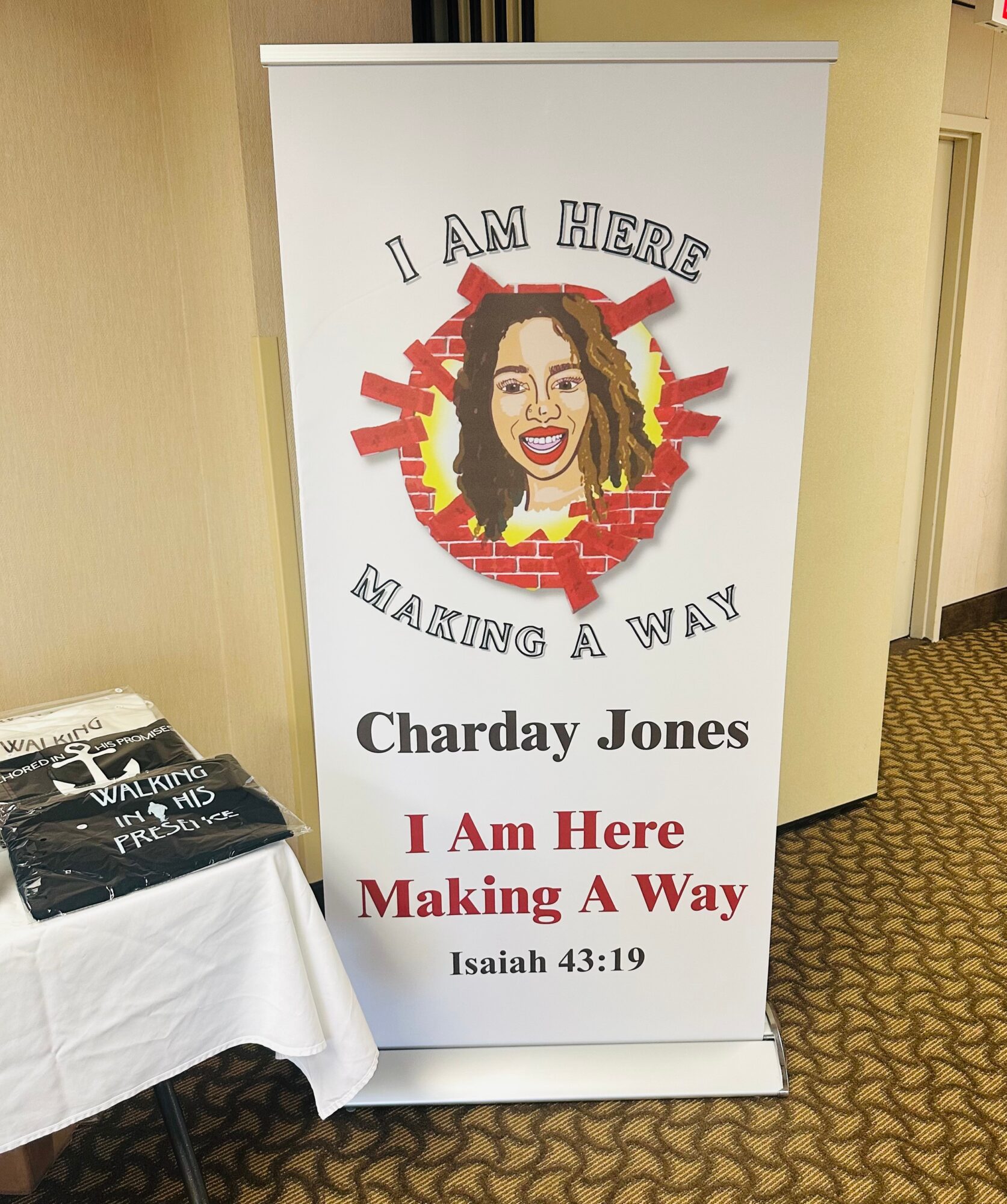 Banner with a woman's face, text 'I am here making a way,' and the name 'Charday Jones,' on a stand.