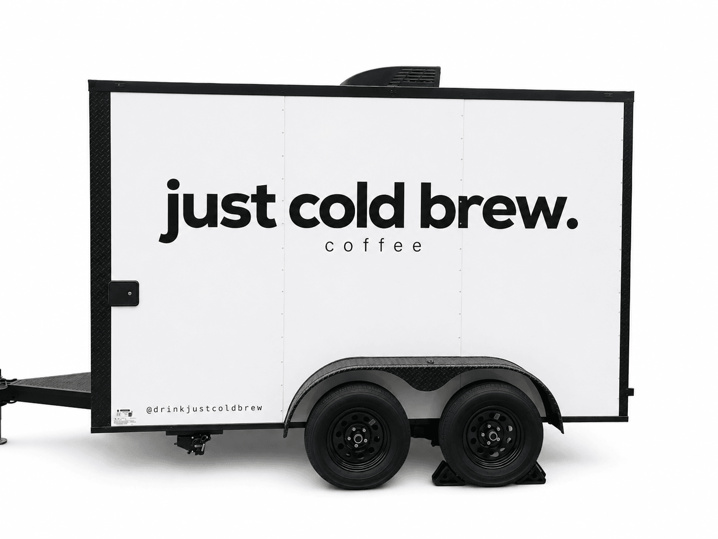 A mobile coffee trailer with a white exterior displaying the text 'just cold brew.' in bold black letters.