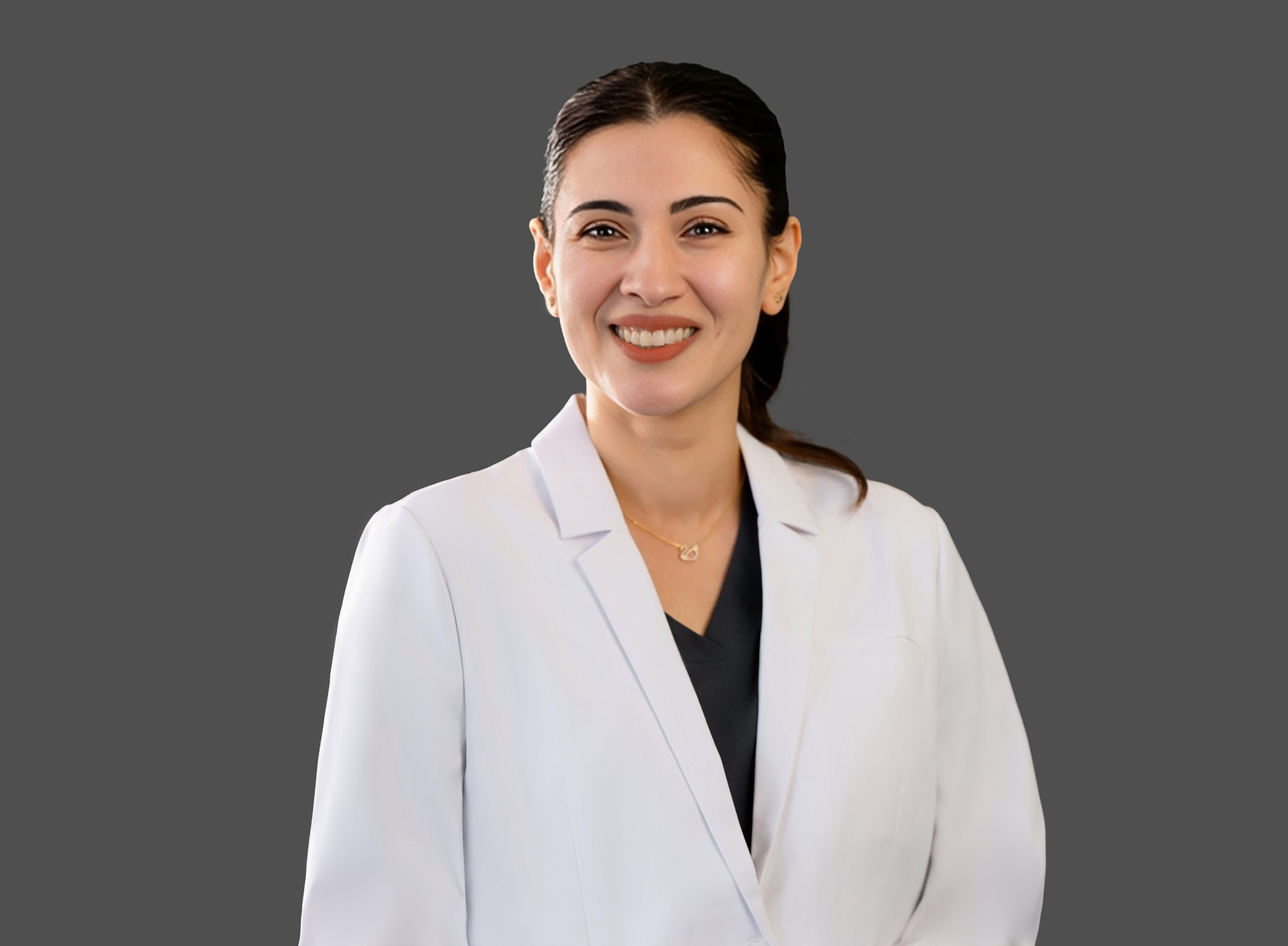 Smiling woman in white blazer and dark top against gray background.