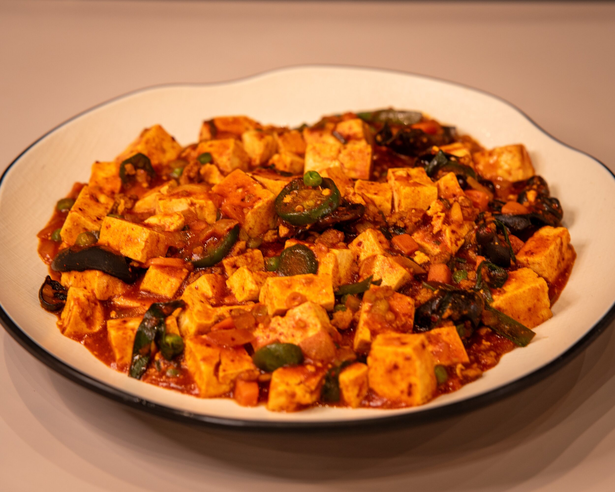 Dish with cubed tofu, green vegetables, and sauce on a white plate, viewed from above.