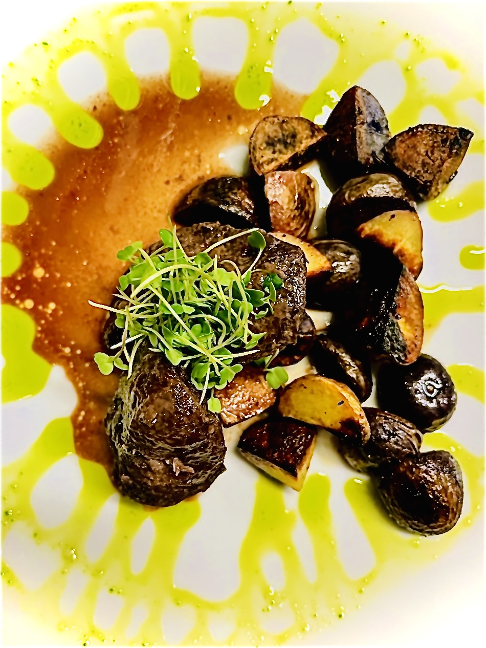 Plate with cooked meat, roasted eggplant, and green garnish, on a yellow and white patterned dish.