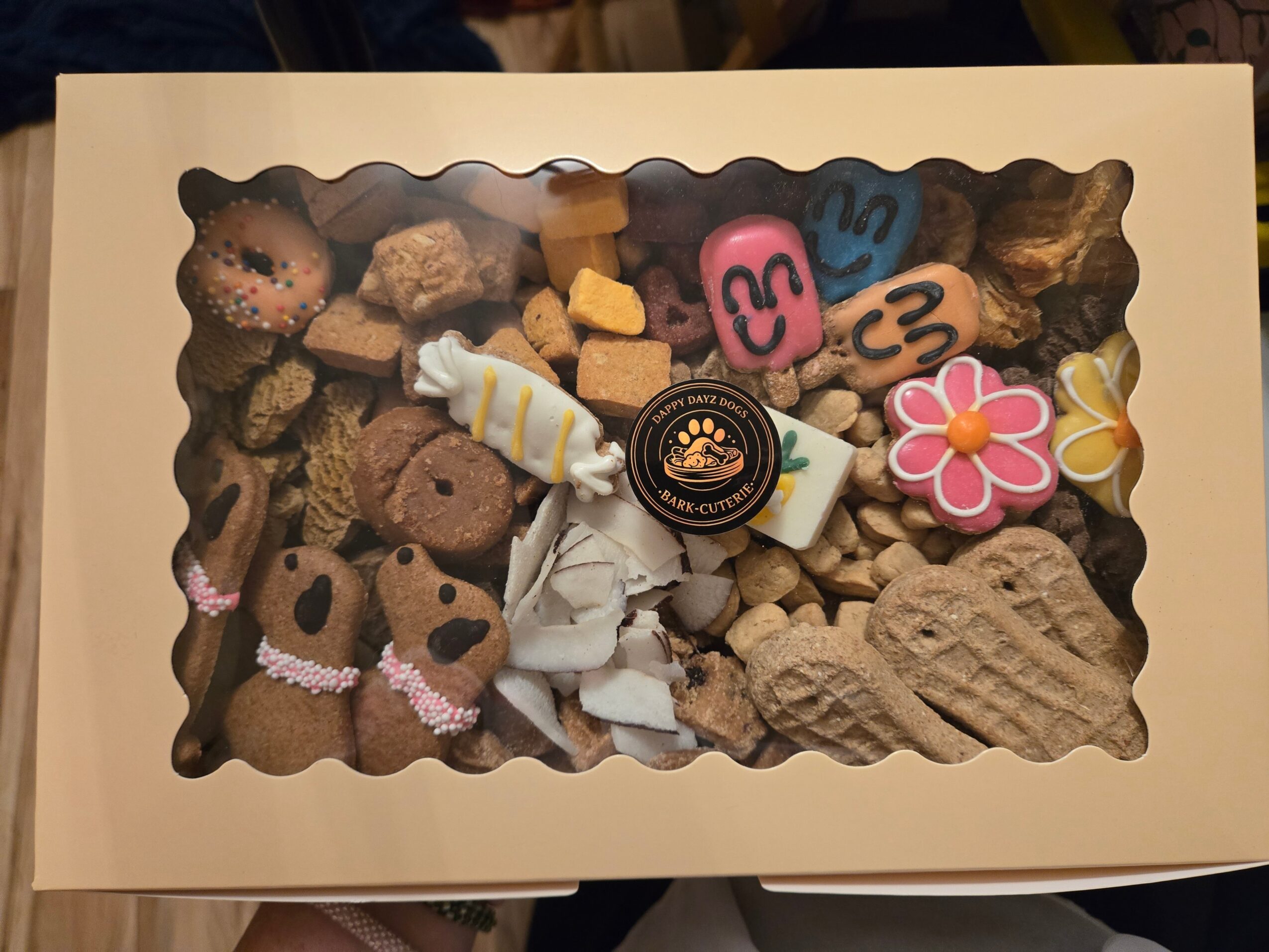 Box of assorted cookies and candies with colorful decorations and packaging, viewed from above.