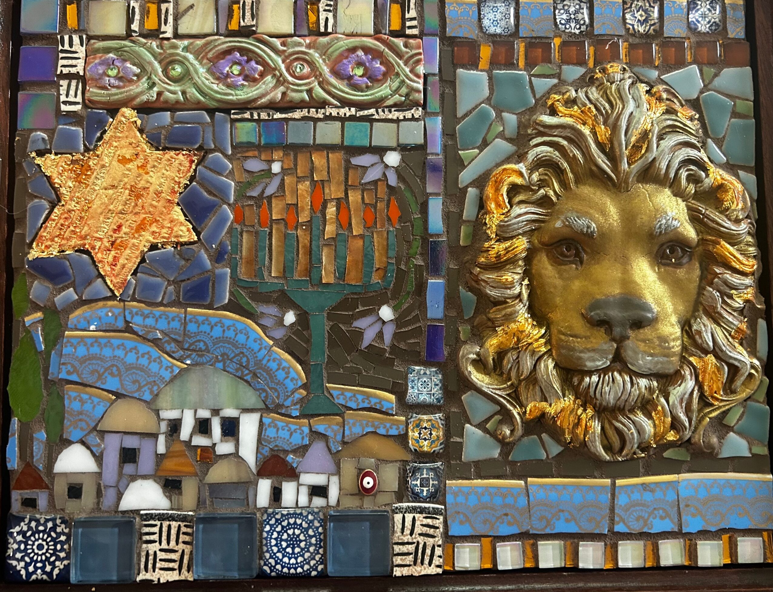 Mosaic artwork with a lion's head, star, and various colorful geometric patterns, including houses and abstract shapes.