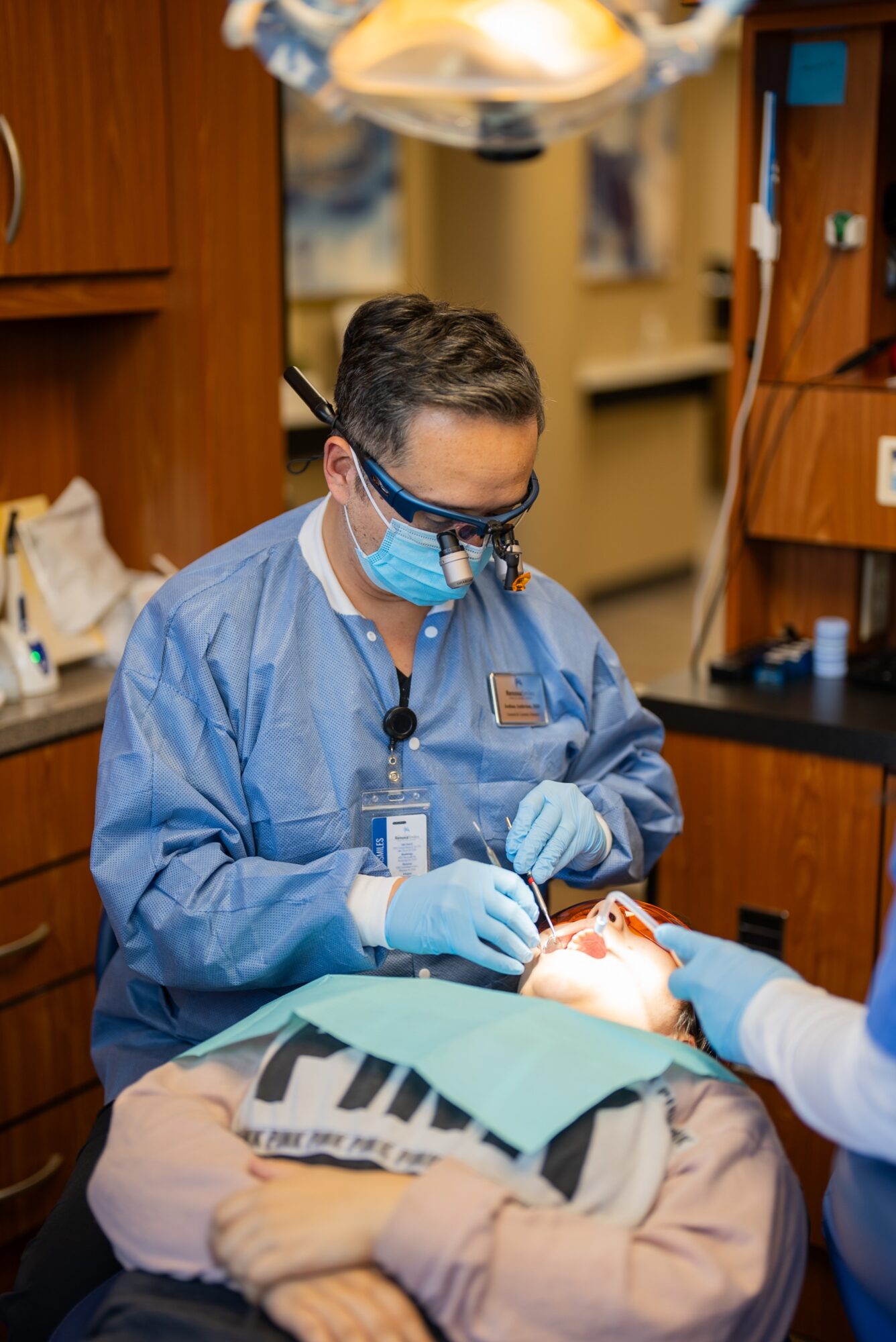 Medical professional in blue scrubs and mask performs surgery in an operating room.