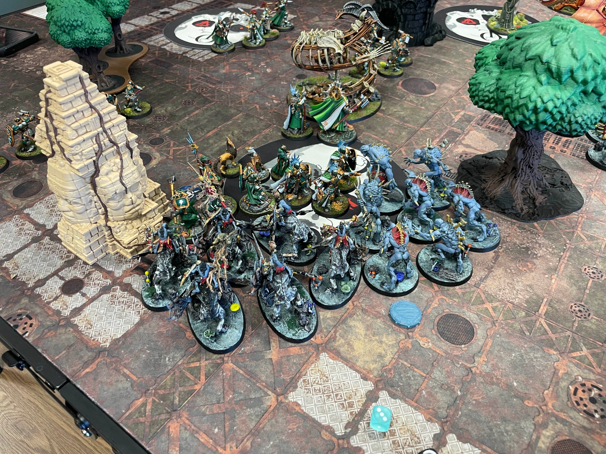 Miniature figures of soldiers and creatures arranged on a tabletop with trees and terrain features.