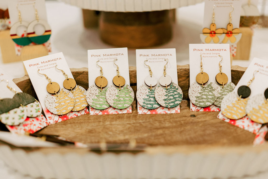 Display of handmade earrings and accessories on a table, featuring Christmas-themed designs and decorations.