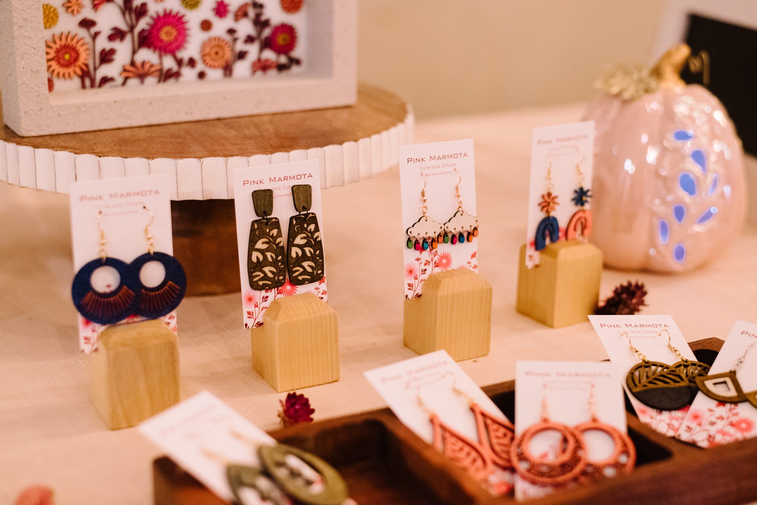 Display of jewelry on a table with decorative items, including earrings and necklaces, in a cozy setting.