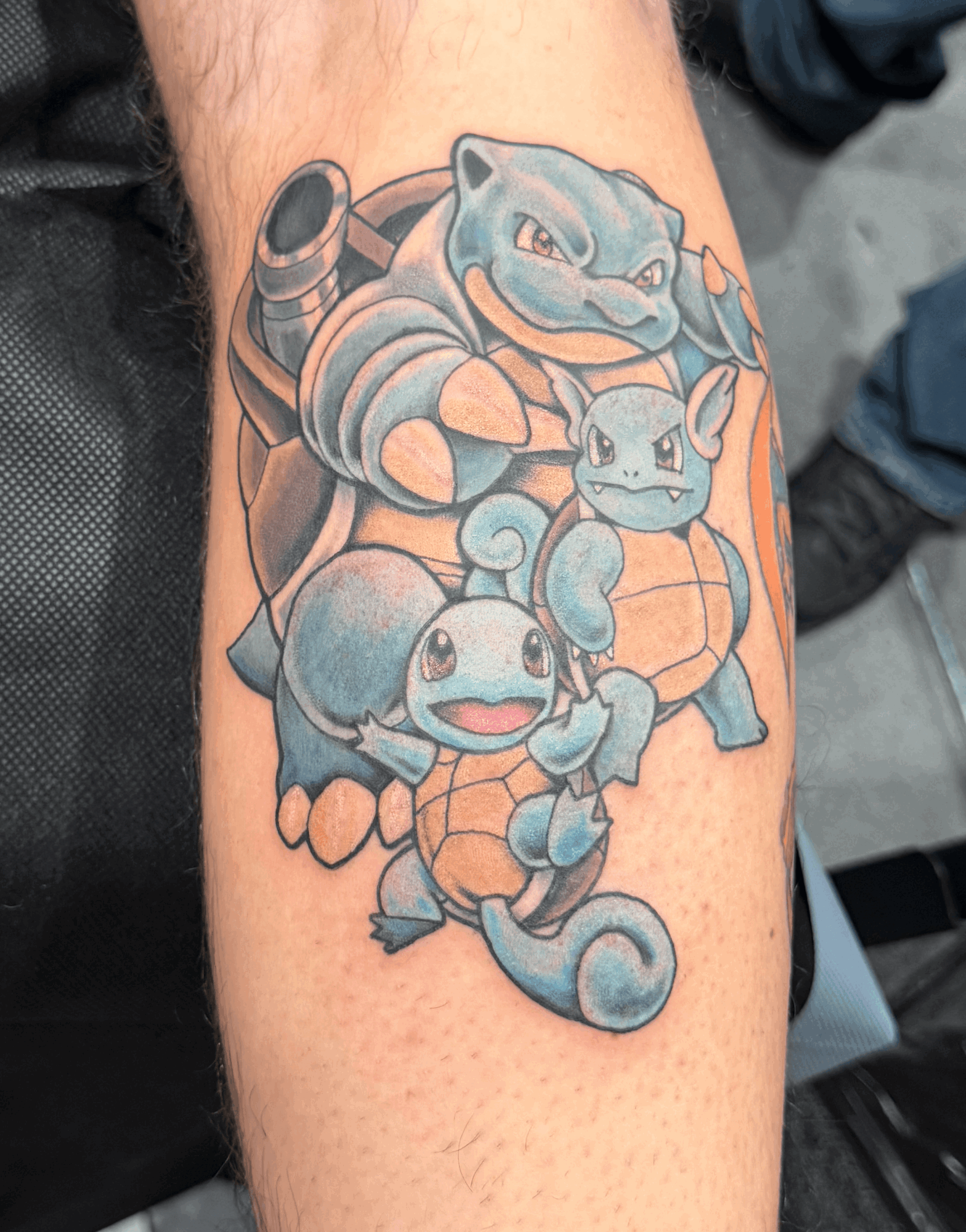 Tattoo of three Pokémon characters, including Blastoise, Squirtle, and another Squirtle, on a person's arm.