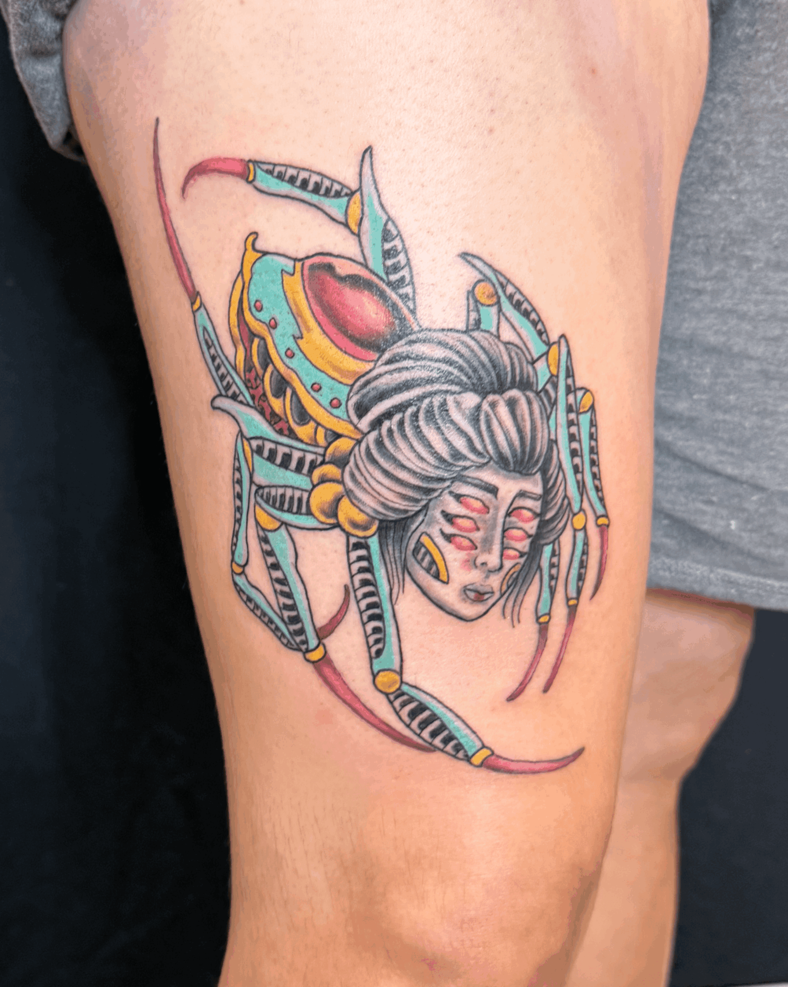 Colorful spider with a woman's face on its body, detailed with vibrant patterns and a serene expression.