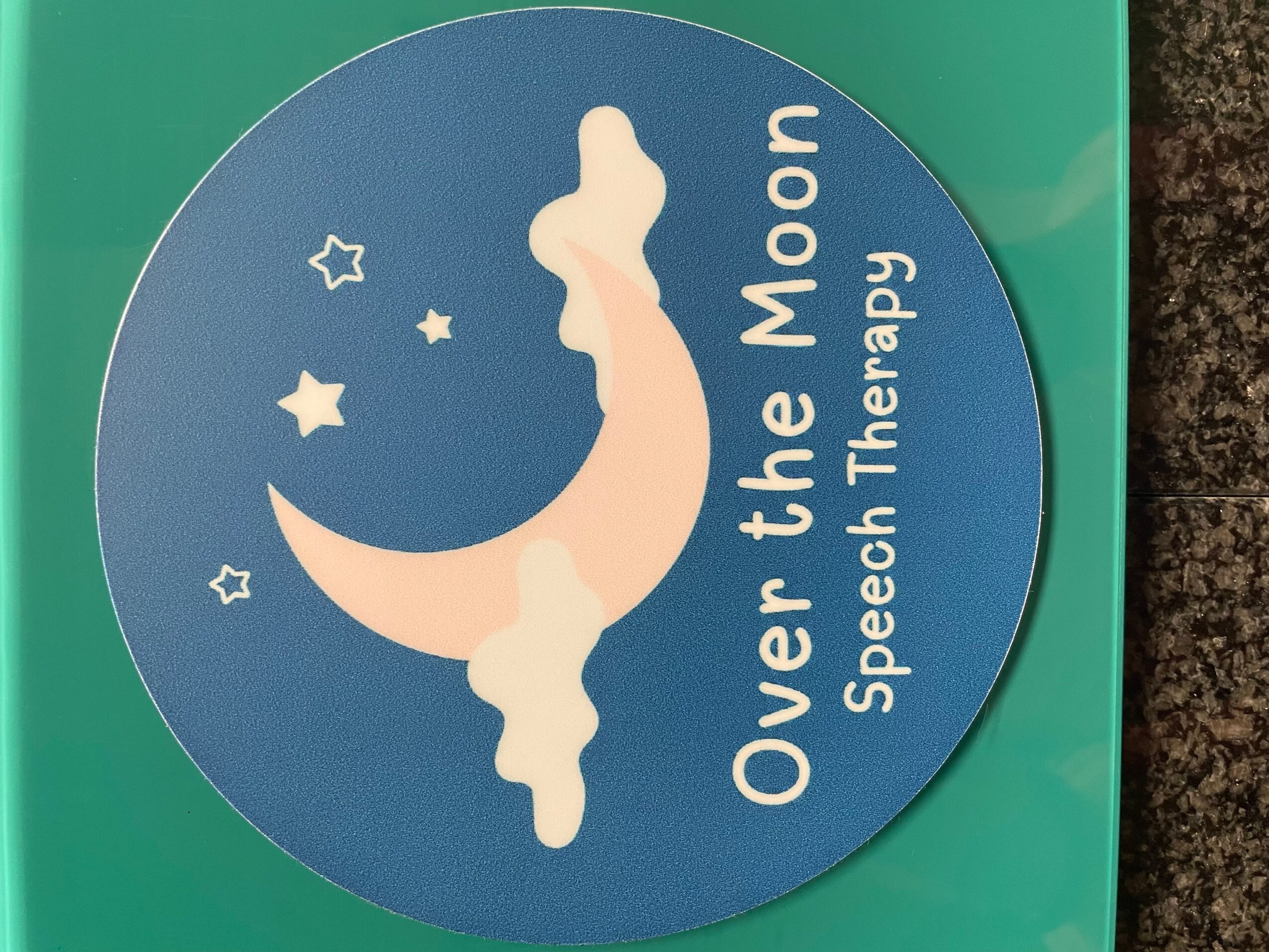 Round blue sticker with a moon and clouds, text reads 'Over the Moon Speech Therapy'.