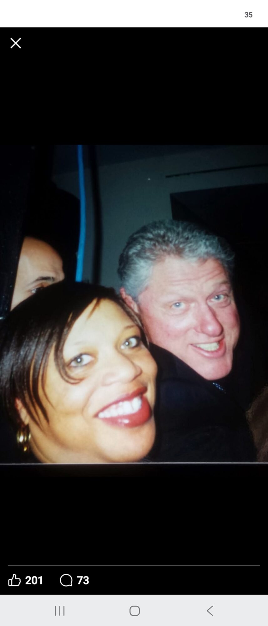 Two people smiling, one with dark hair and the other with gray hair, in a close-up photo.