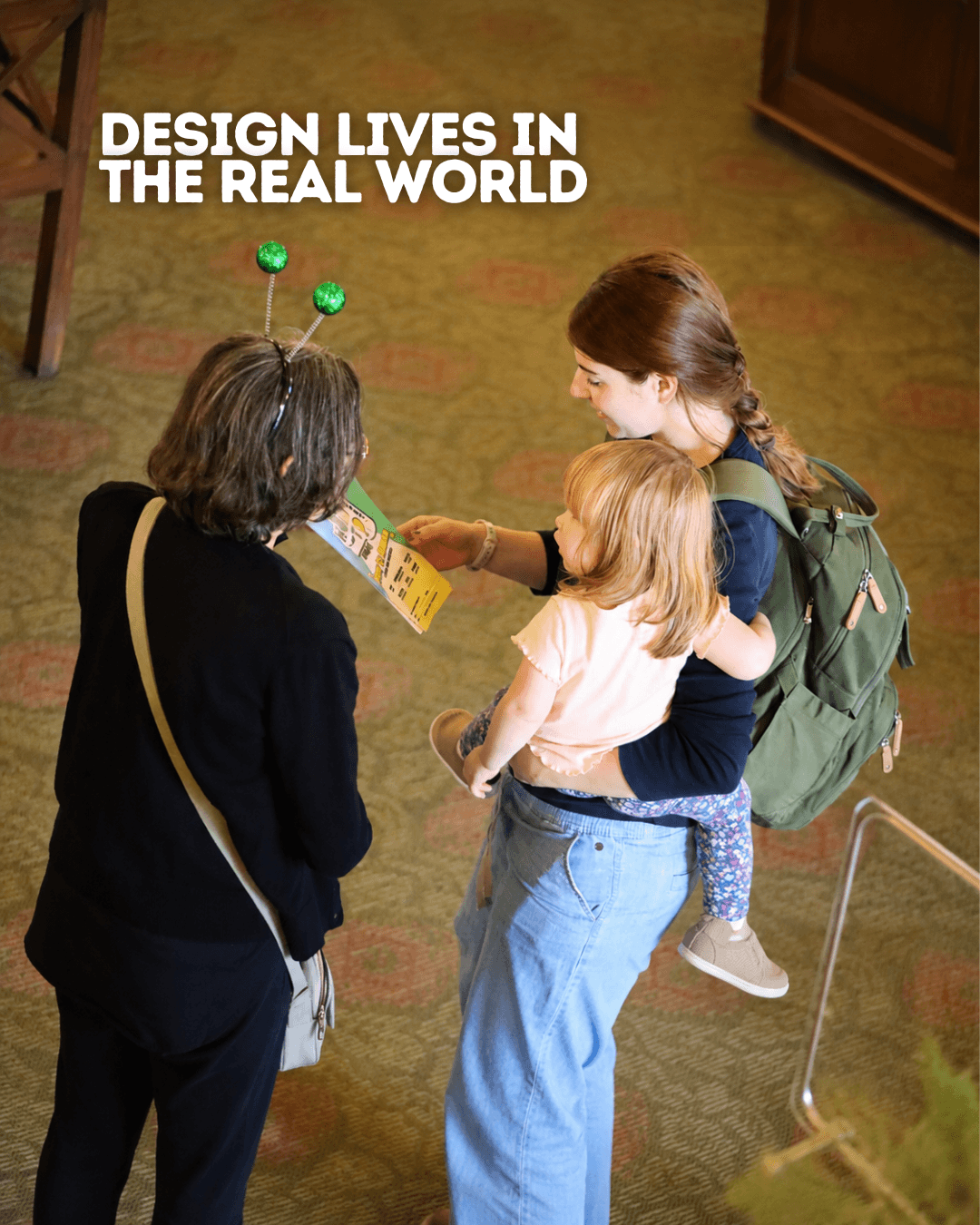 Two women and a child look at a brochure in a room with a green carpet and wooden furniture, with text 'Design lives in the real world'.