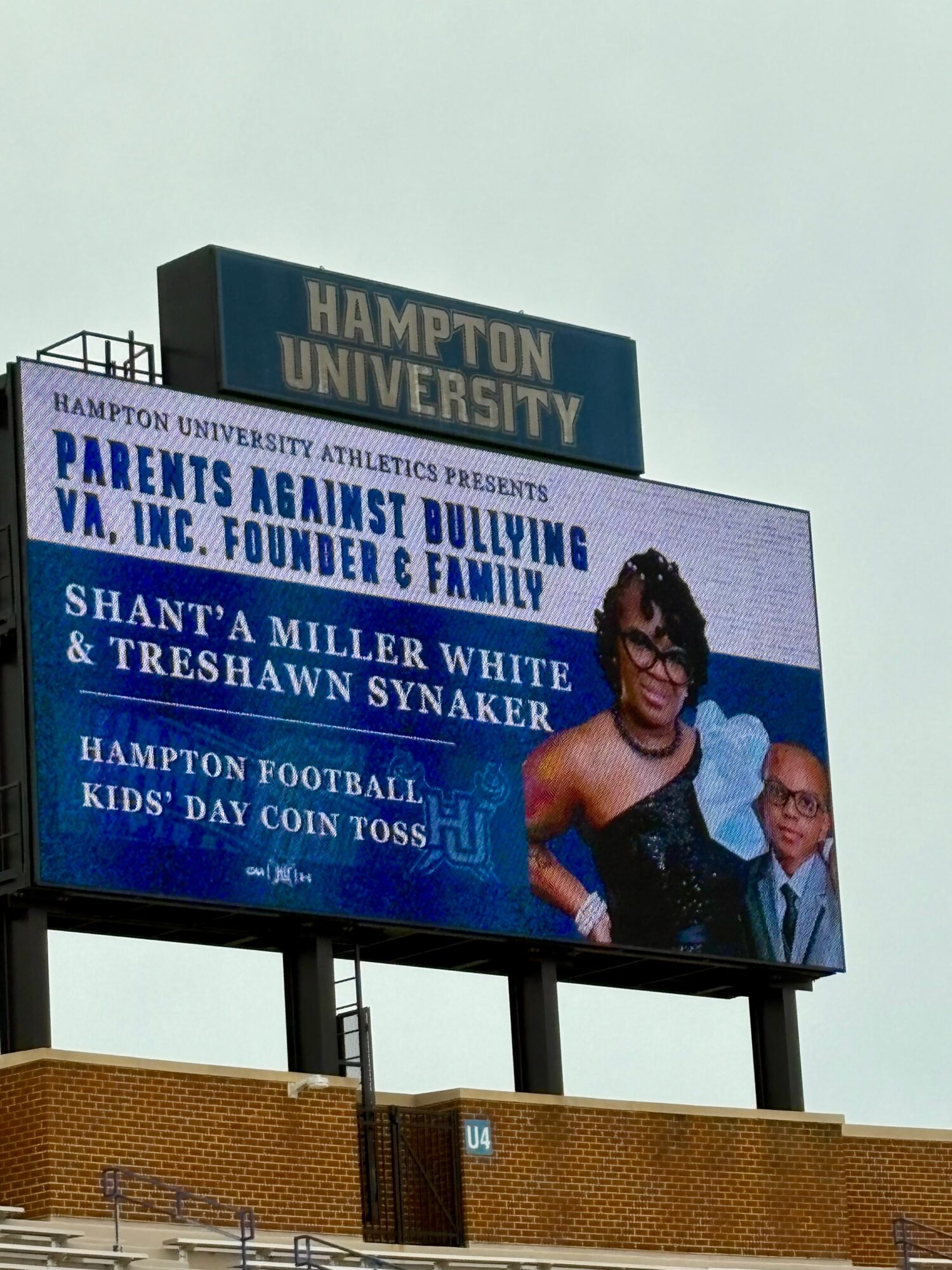 Digital billboard displays an event announcement with a woman and a man, promoting a parents against bullying event at Hampton University.