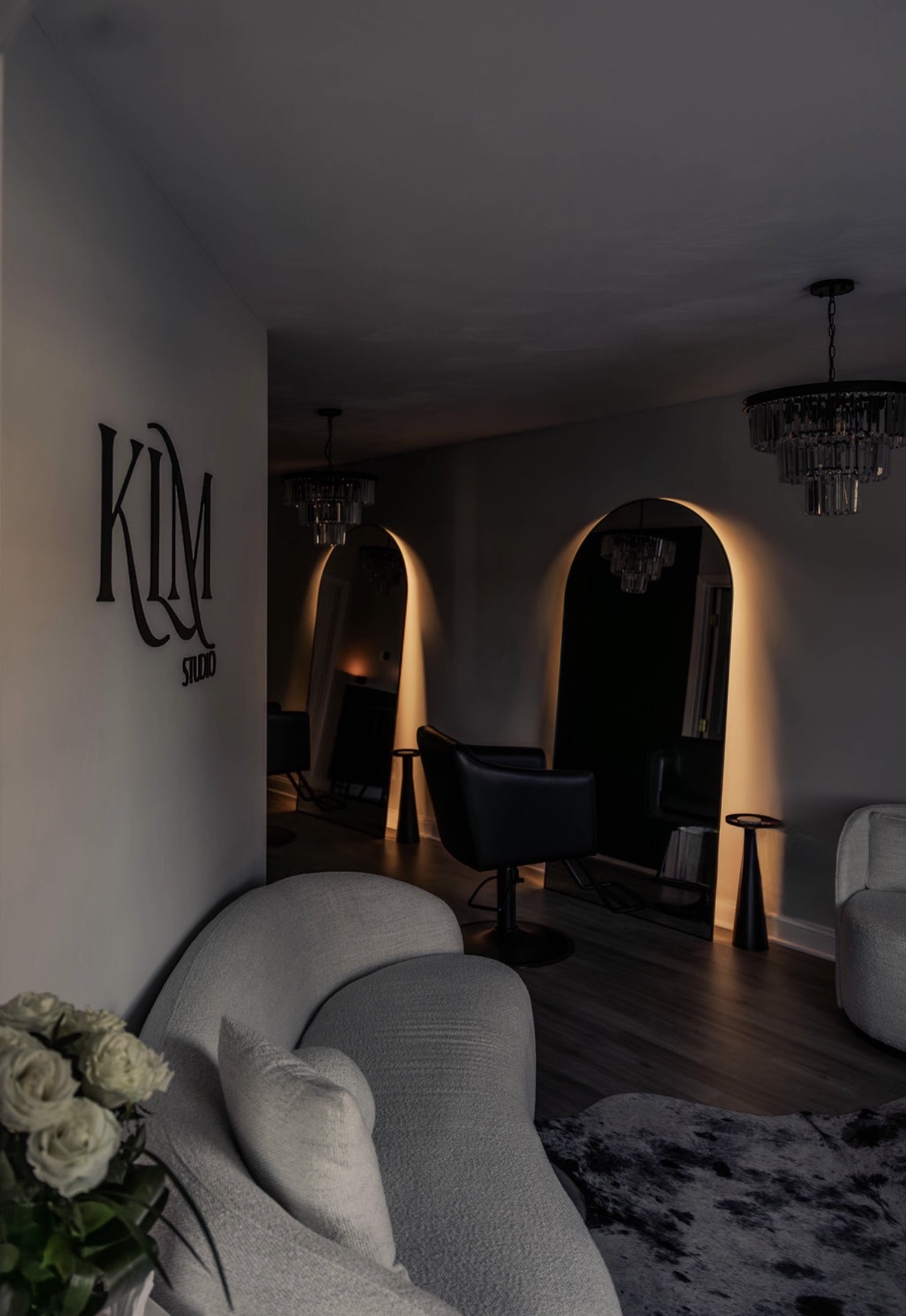 Living room with arched doorways, chandelier, armchair, and a wall with decorative letters, with a rug on the floor.