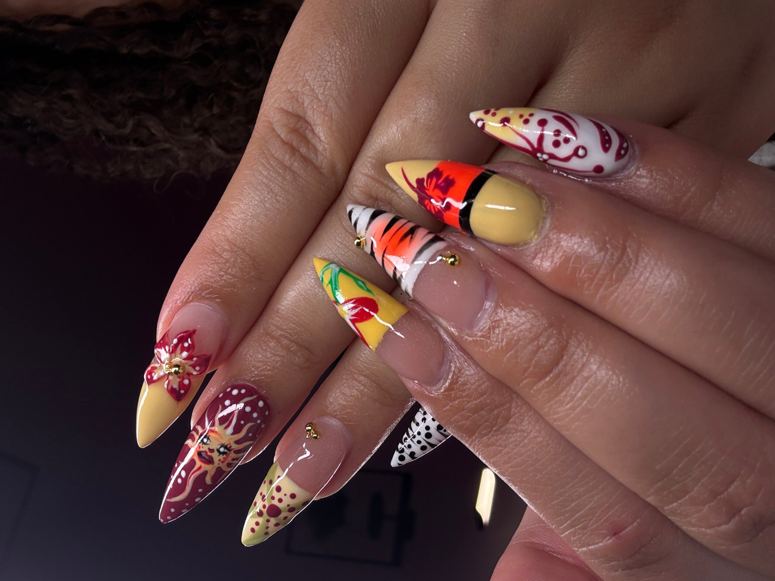 Close-up of hands with colorful, decorated long nails featuring various patterns and designs.