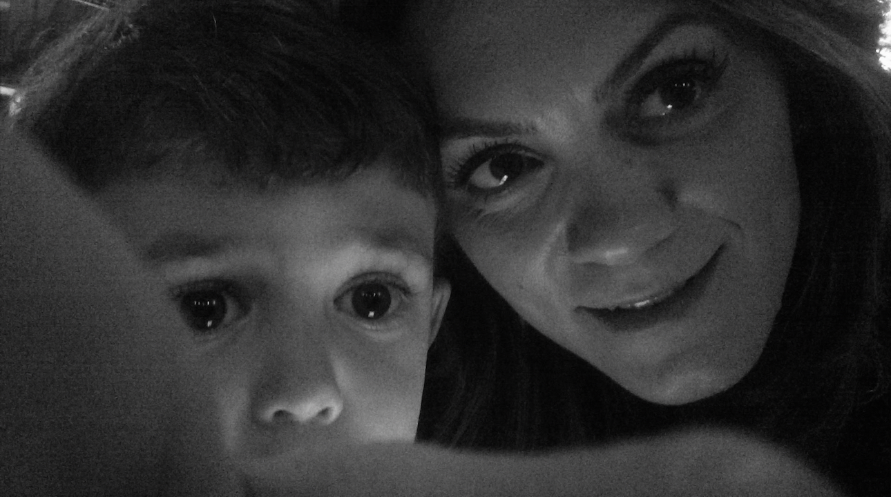Close-up of a woman and a young boy, both looking at the camera, with their faces close together in black and white.