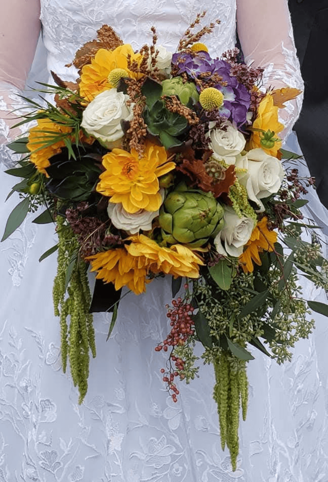 Person in white dress holding a colorful bouquet with yellow, purple, white flowers and greenery.