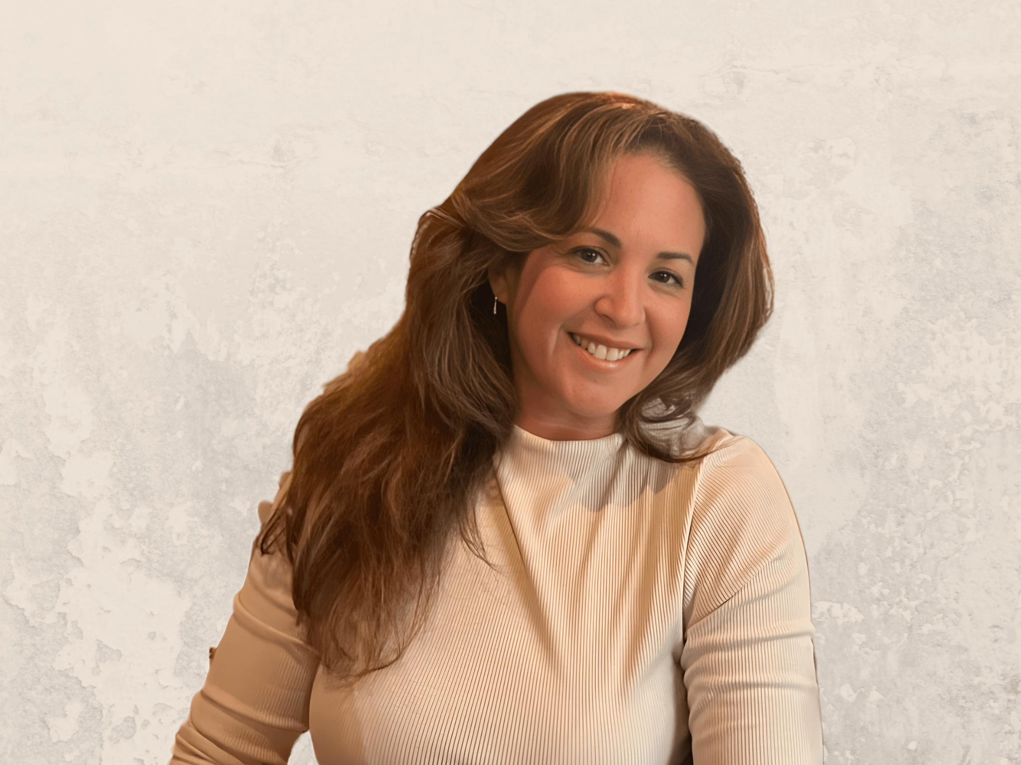 Woman with long wavy hair smiling, wearing a light-colored top, against a plain background.