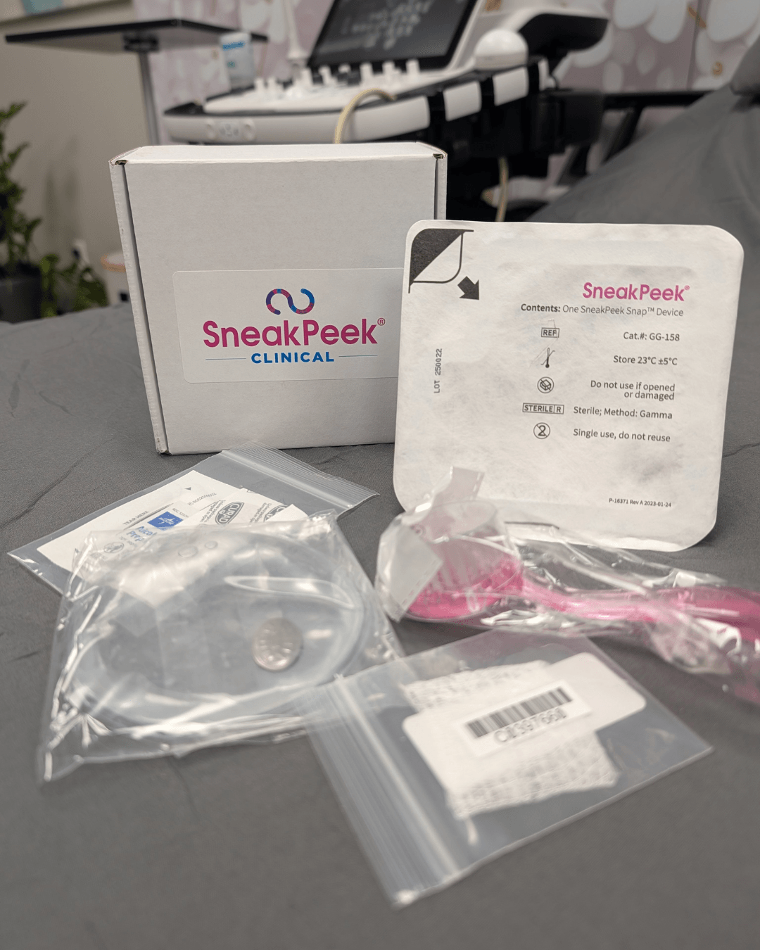 Medical testing kit with box, swab, and sealed packaging on a gray surface, background includes a keyboard and electronic device.