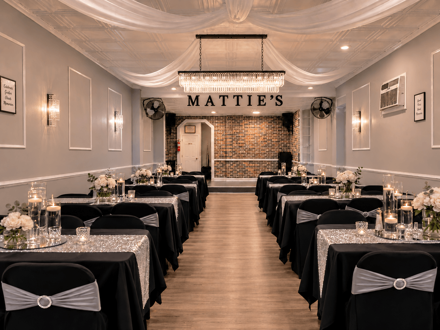 Event space with tables covered in black cloths, decorated with glassware and flowers, and a sign reading 'MATTIE'S' at the back.