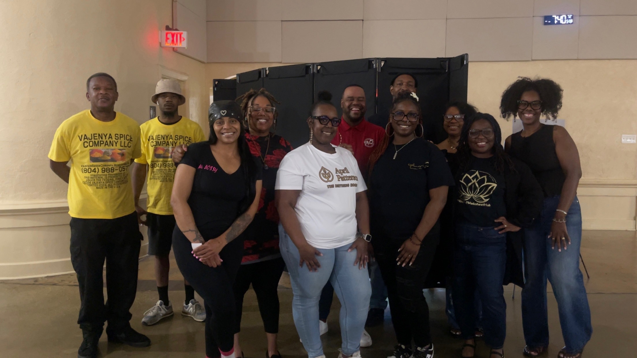 Group of ten people standing indoors, some wearing yellow shirts, others in casual clothing, smiling for the photo.