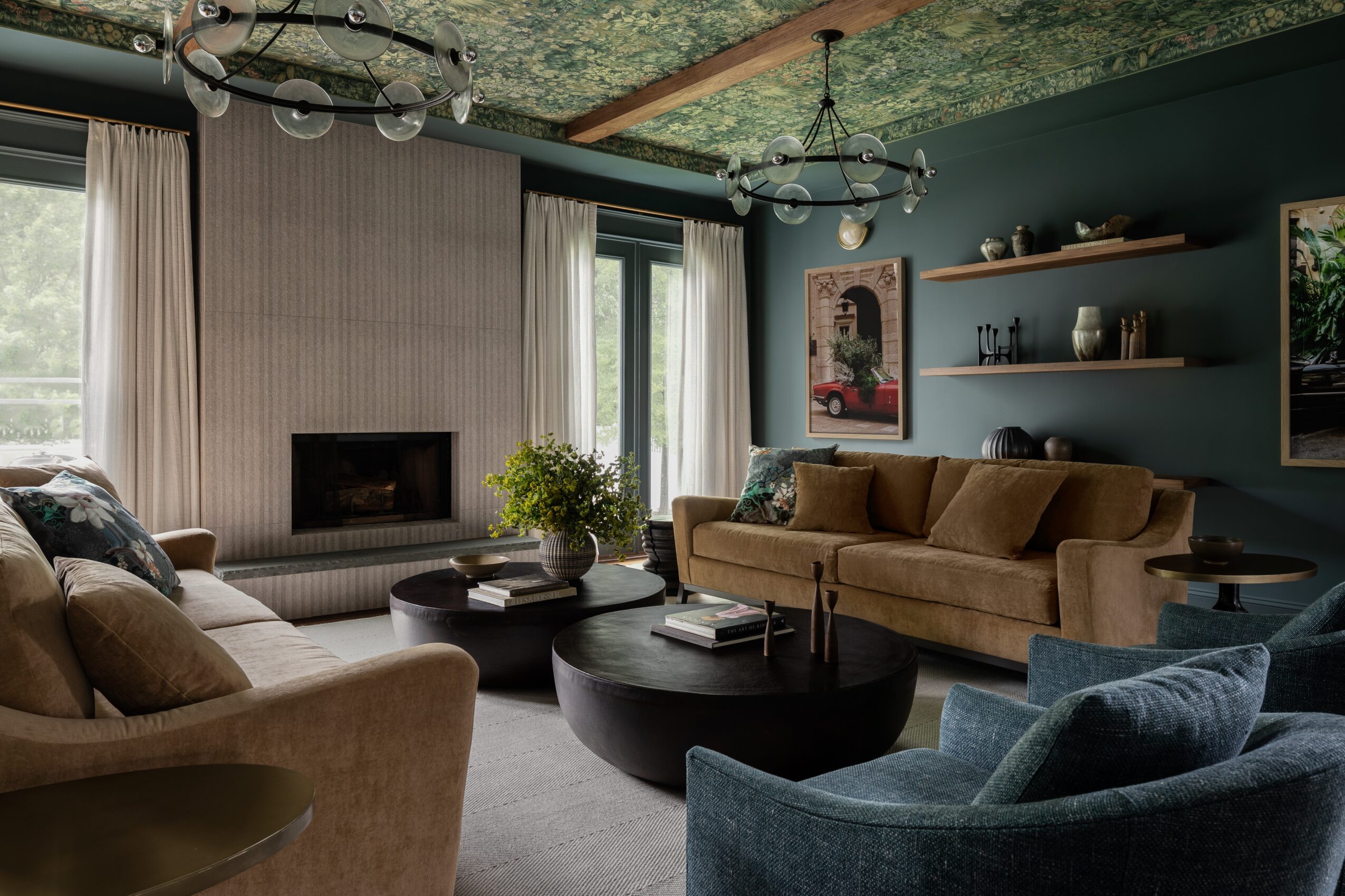 Living room with large windows, beige and blue chairs, a brown sofa, a fireplace, and wall shelves with decor.