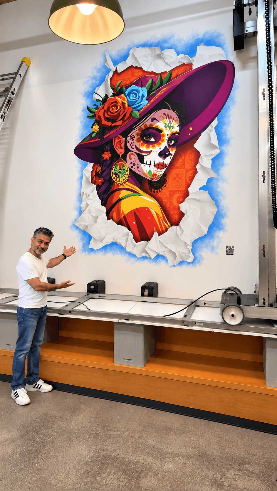 Colorful mural of a woman with a decorated skull face, wearing a large purple hat with roses, on a torn paper background.