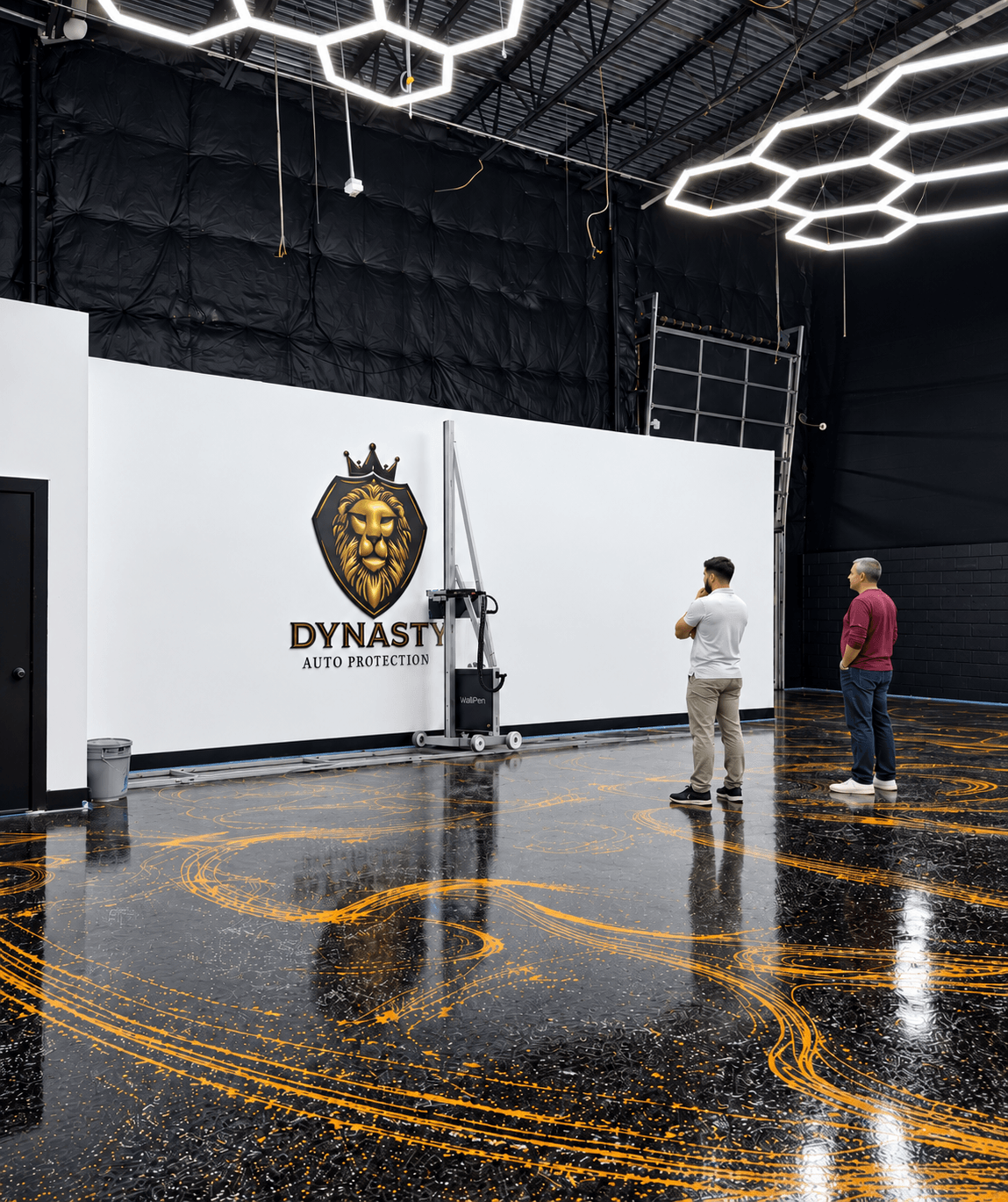 Two people stand in a spacious indoor area with a shiny black floor and white wall, decorated with a lion logo and text.