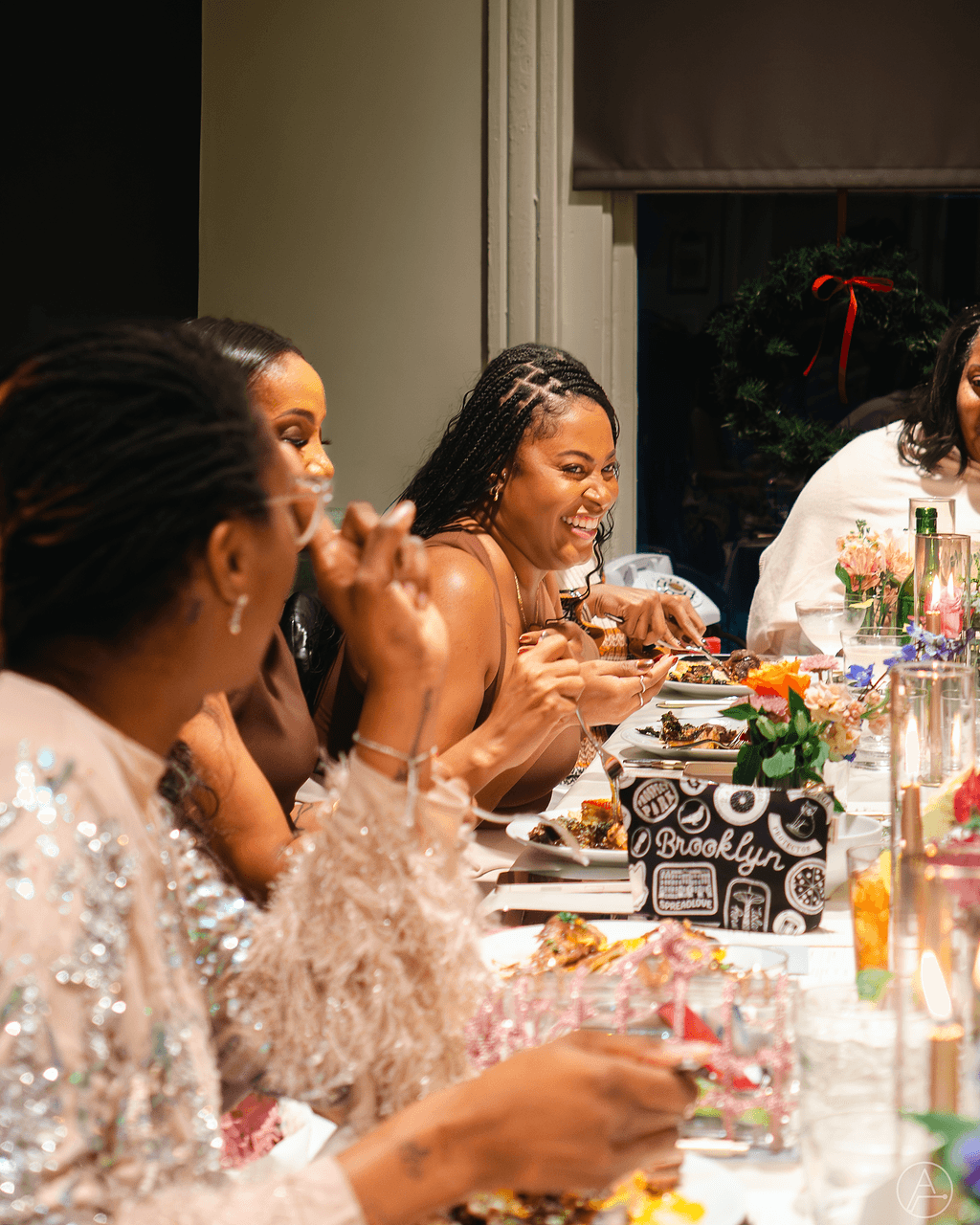 Group of women sitting at a decorated table, smiling and engaging in conversation during a celebration.