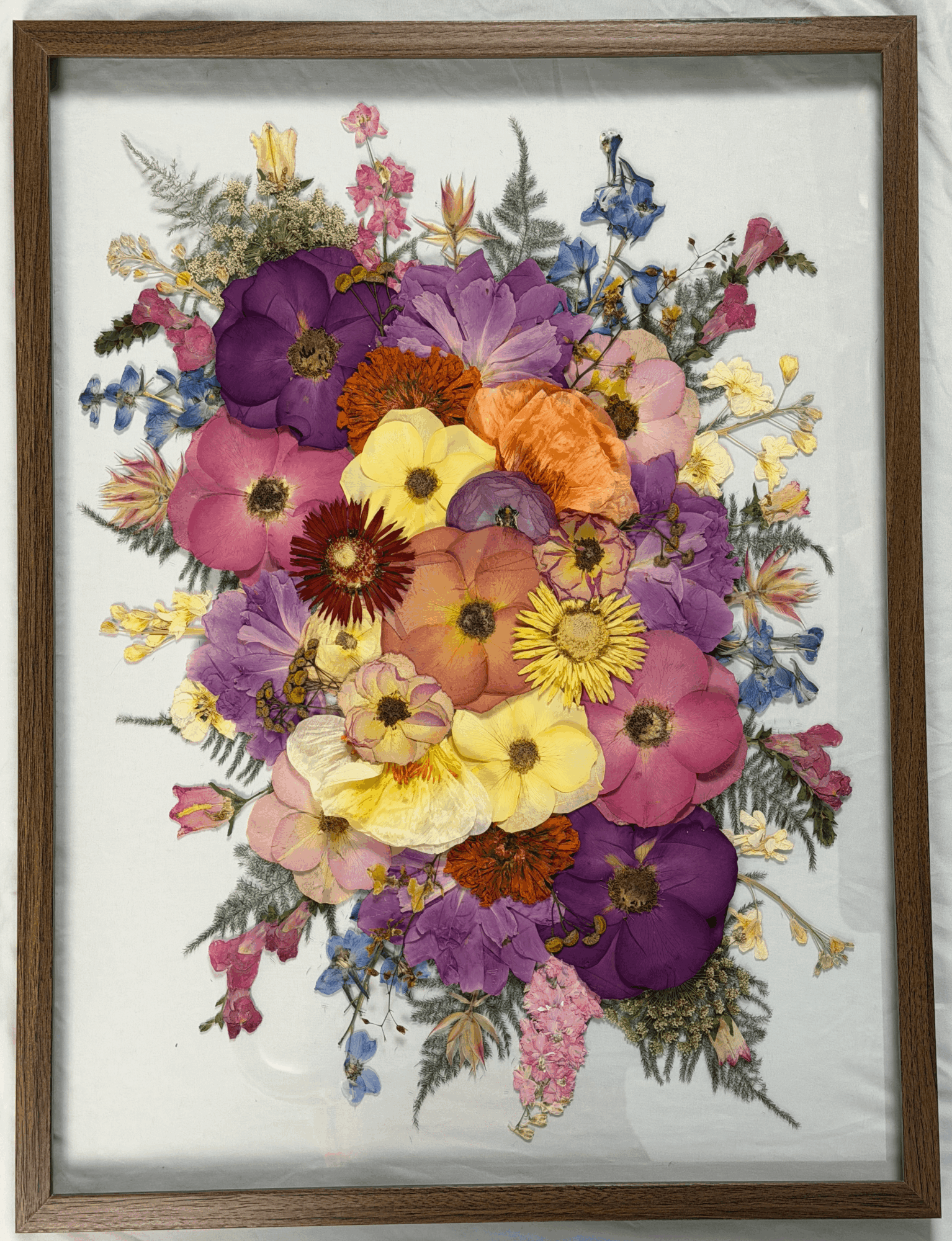 Colorful bouquet of various flowers including purple, pink, yellow, and orange blooms, arranged in a frame.
