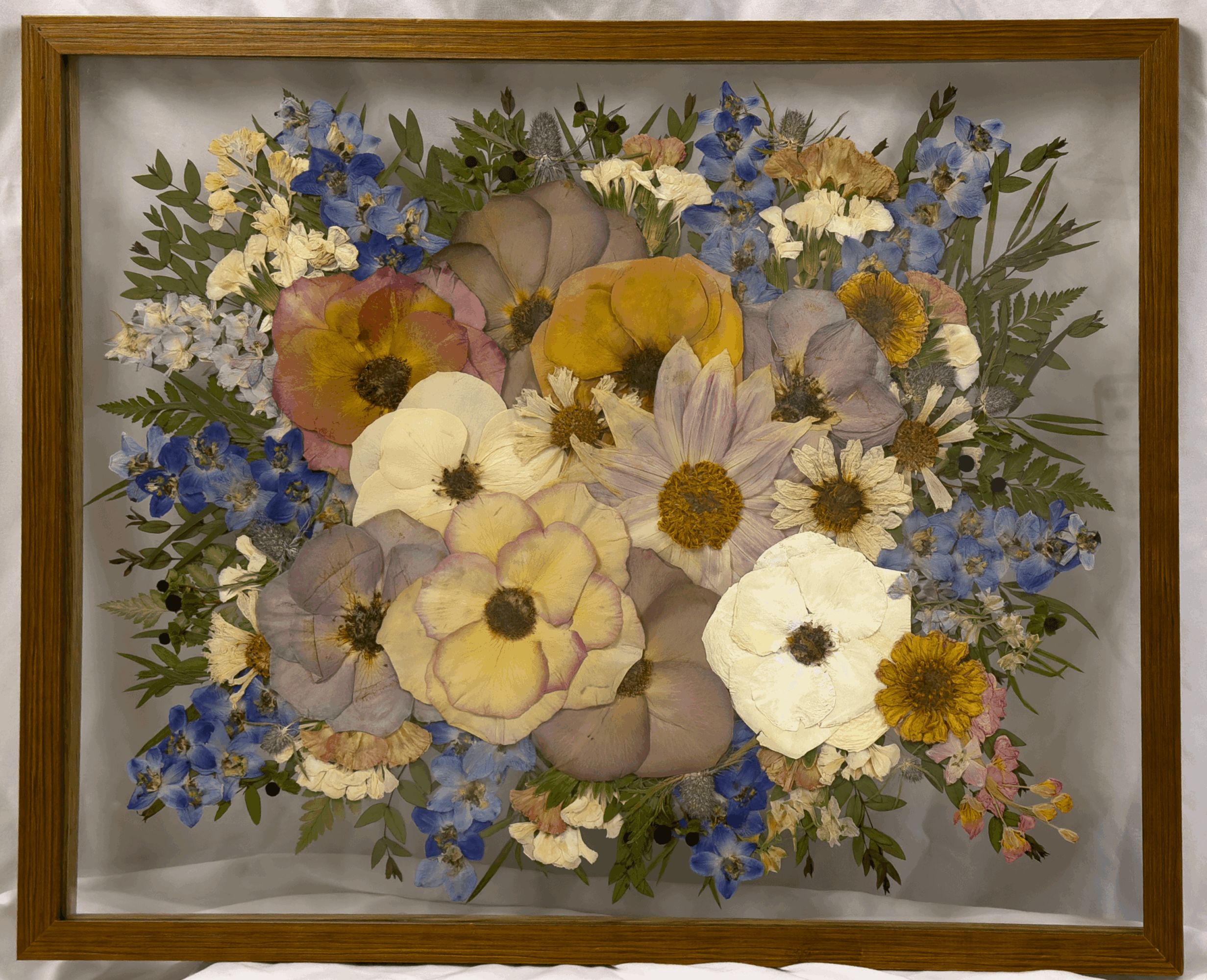 Framed floral painting with colorful flowers including daisies, pansies, and other blooms, in a variety of colors and green foliage.