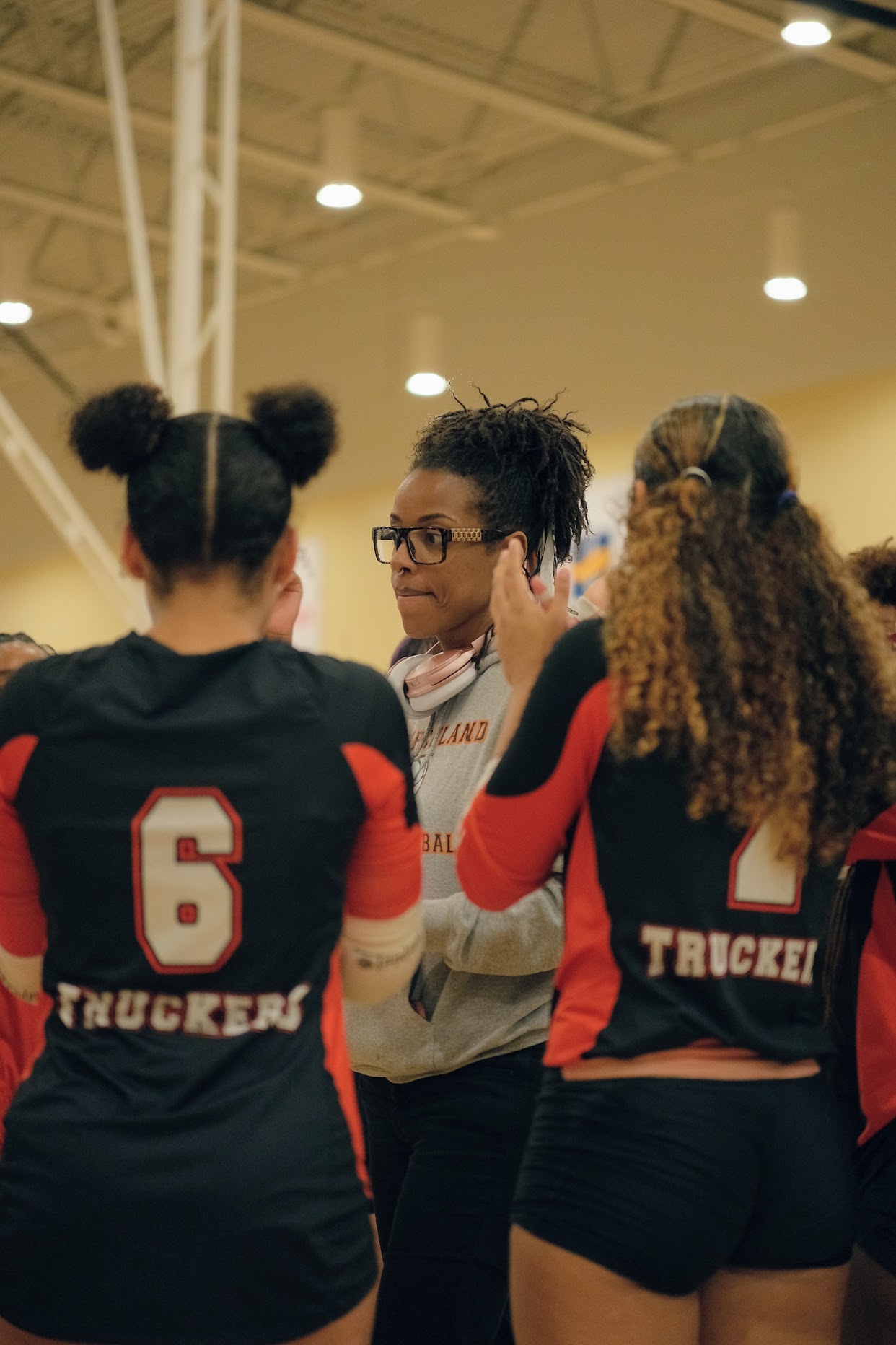Three female volleyball players in black and red uniforms with