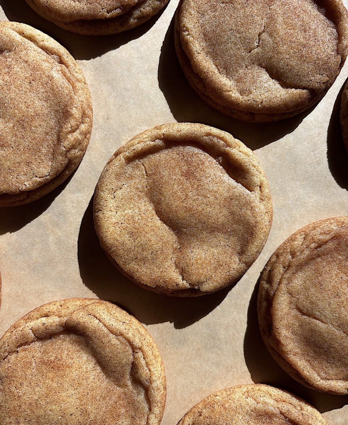 Close-up of round muffins on parchment paper, showing golden-brown tops and slightly cracked surfaces.