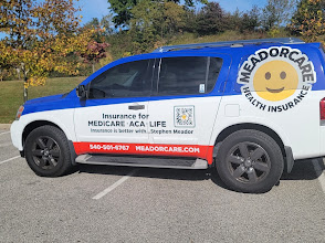 Blue and white vehicle with a smiley face logo and text about insurance, parked outdoors with trees in the background.