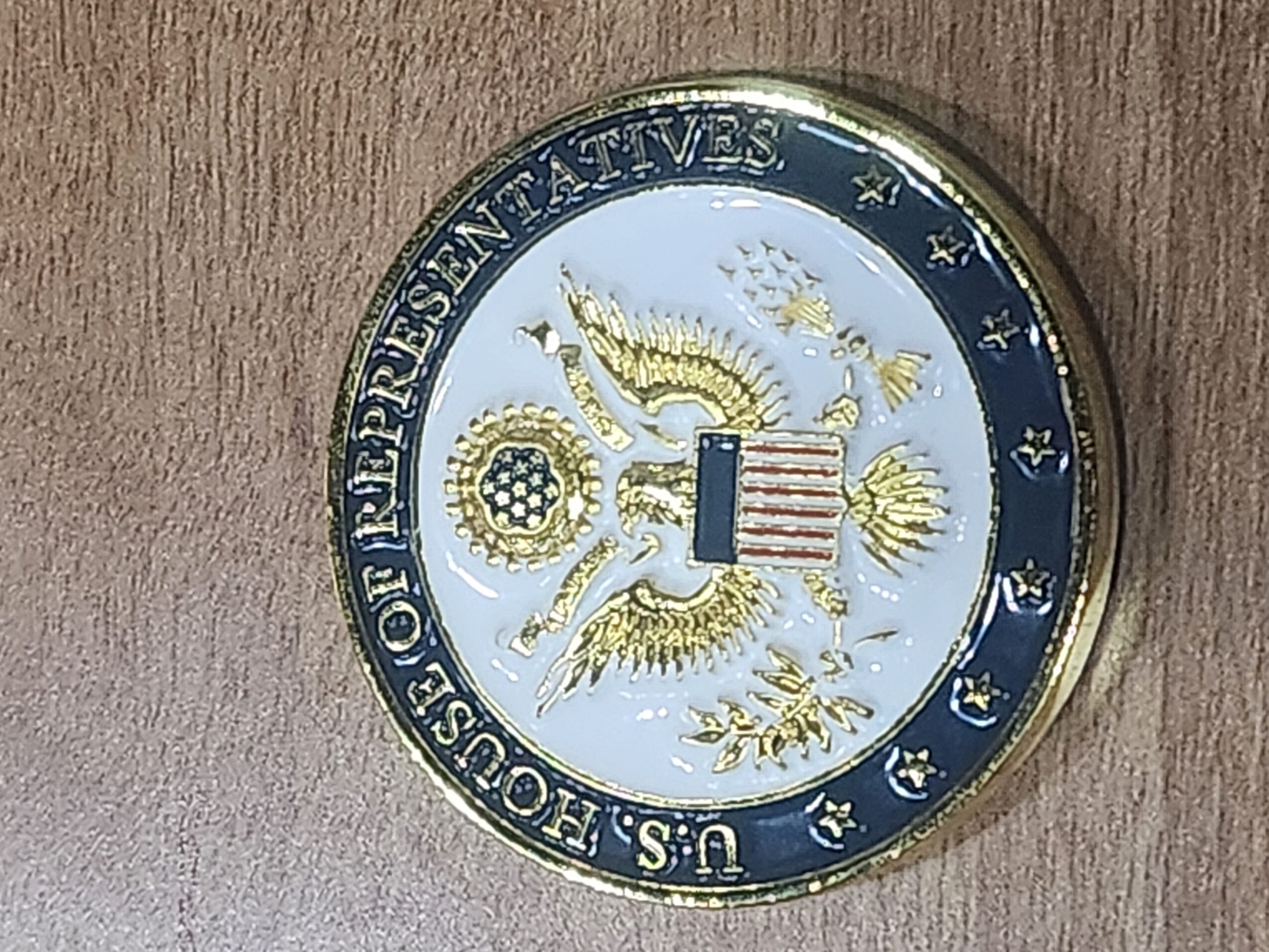 U.S. House of Representatives coin with eagle and shield, text around edge, on wooden surface.