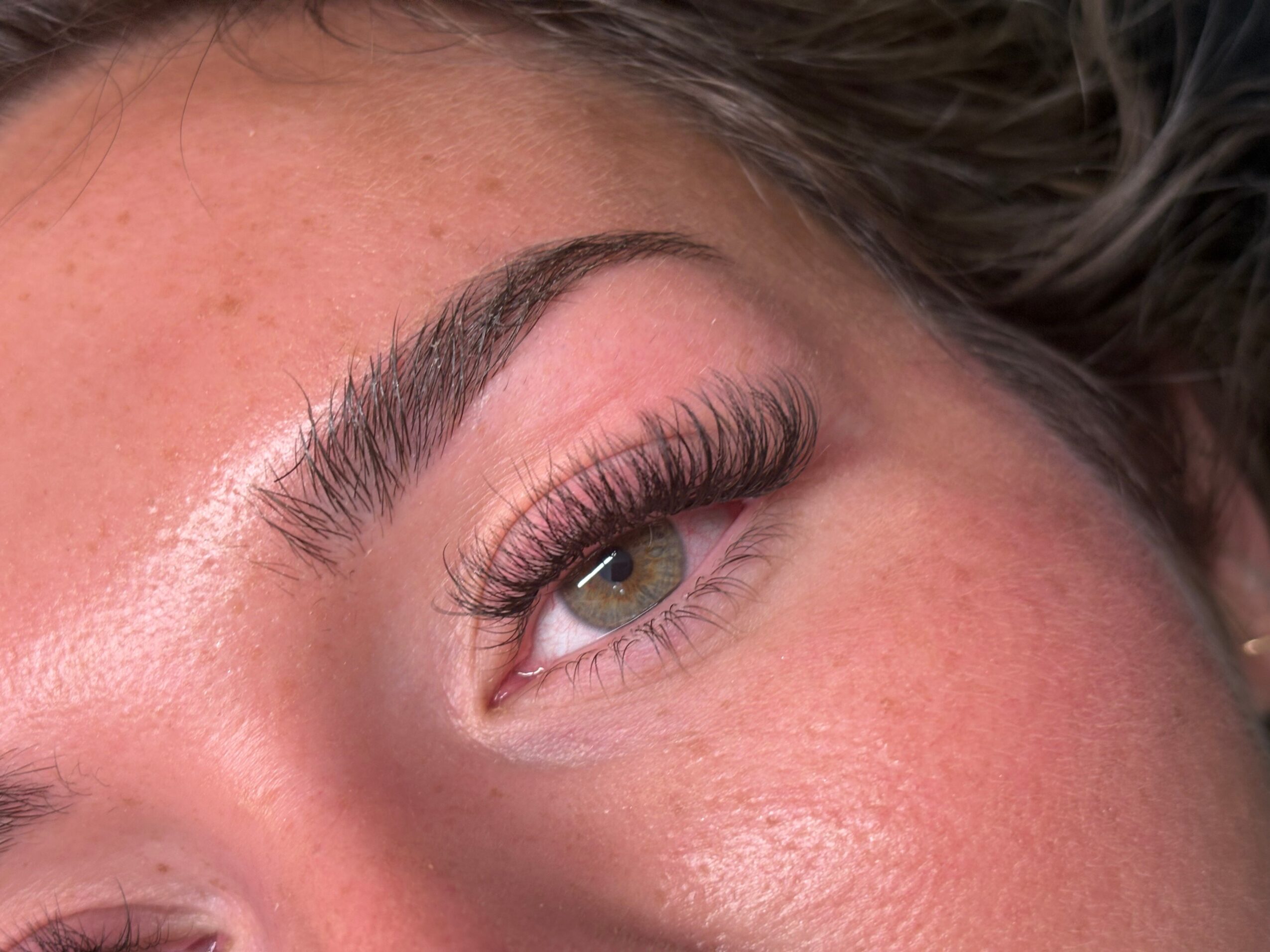 Close-up of a person's eye with makeup, including long eyelashes and well-groomed eyebrow.