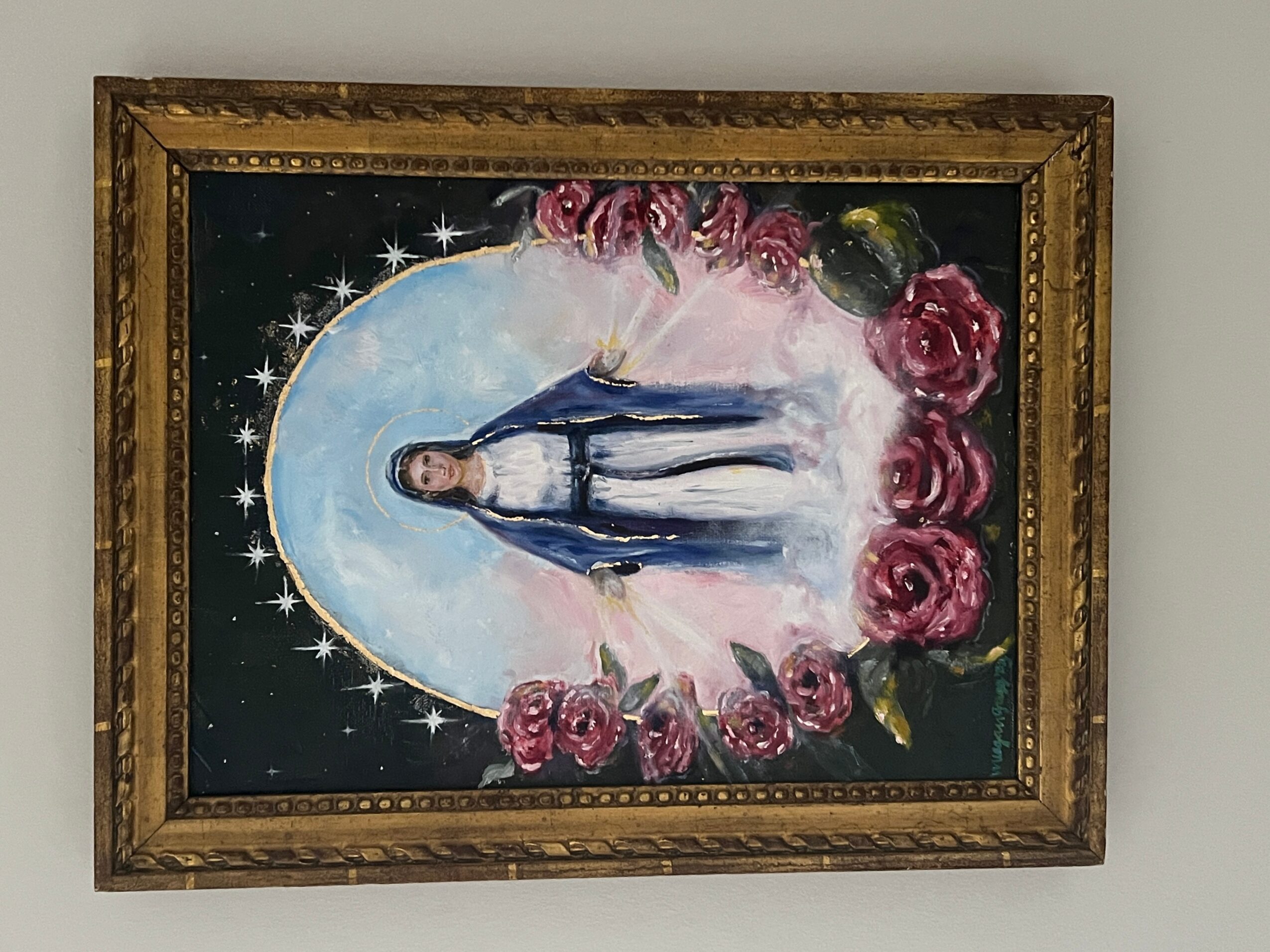 Framed religious painting of a person standing with a halo, surrounded by pink roses and a starry background.