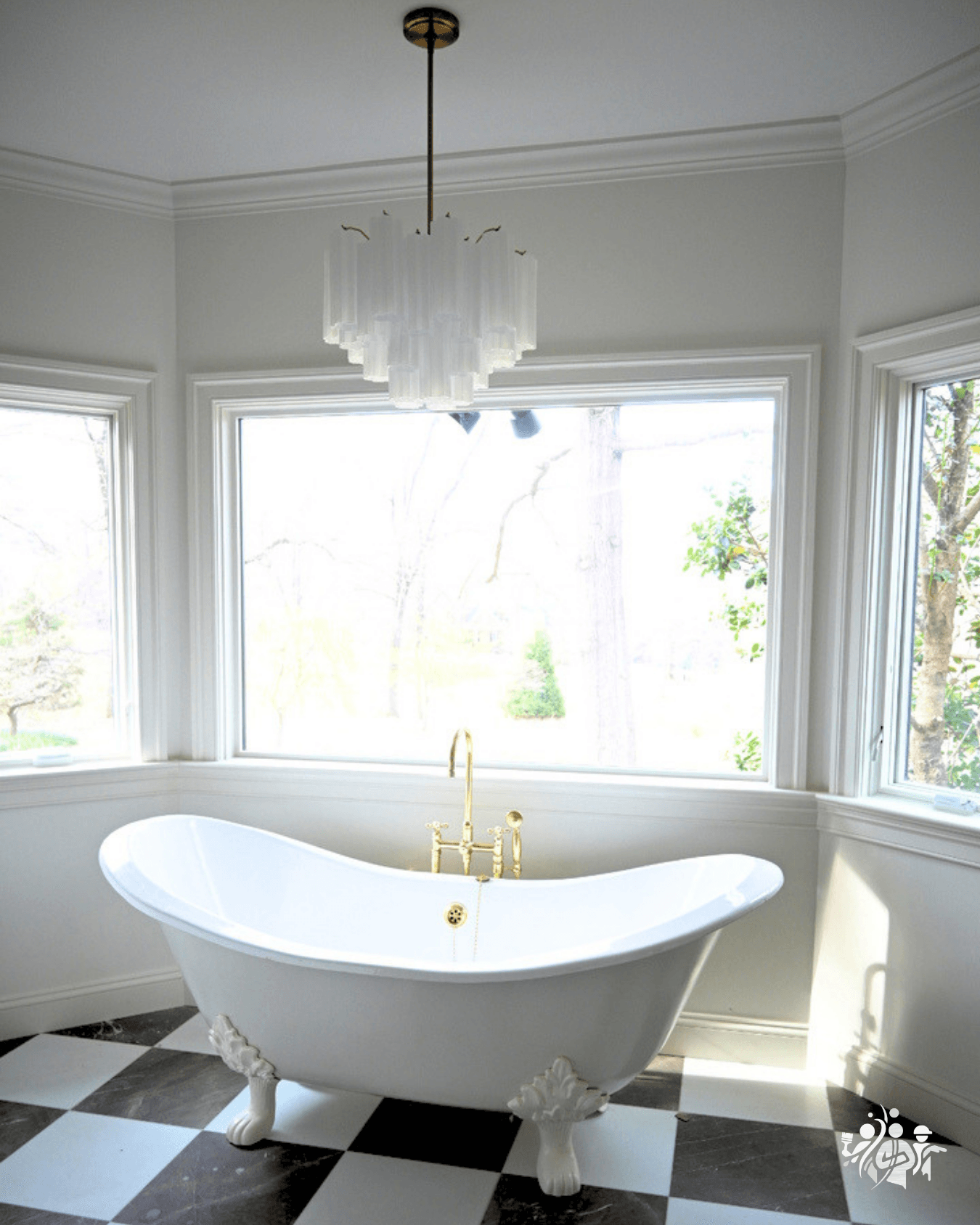 Freestanding bathtub with clawfoot design in a bright bathroom with large windows and checkered floor.