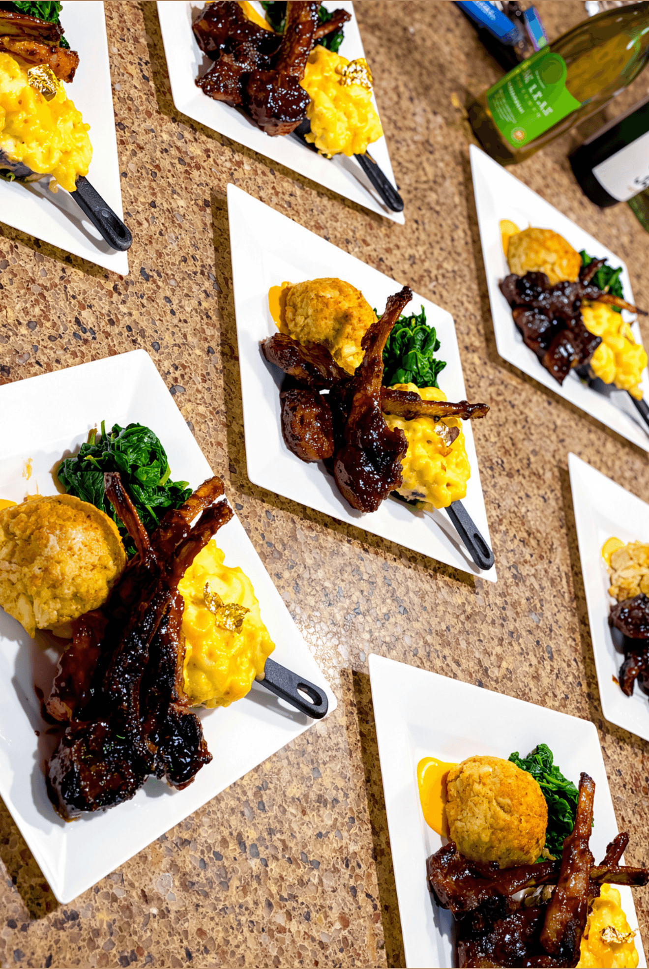 Multiple plates with fried food, vegetables, and dark sauce on a brown table, arranged in a pattern.