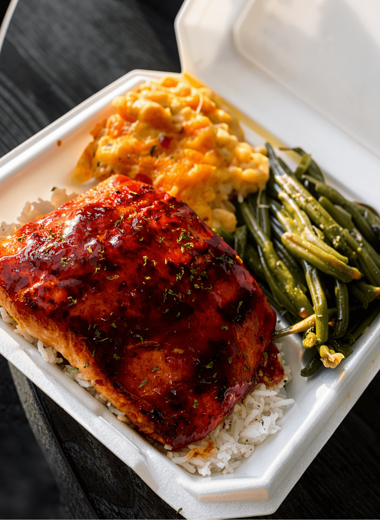 Barbecue chicken, mashed sweet potatoes, green beans, and rice in a takeout container.
