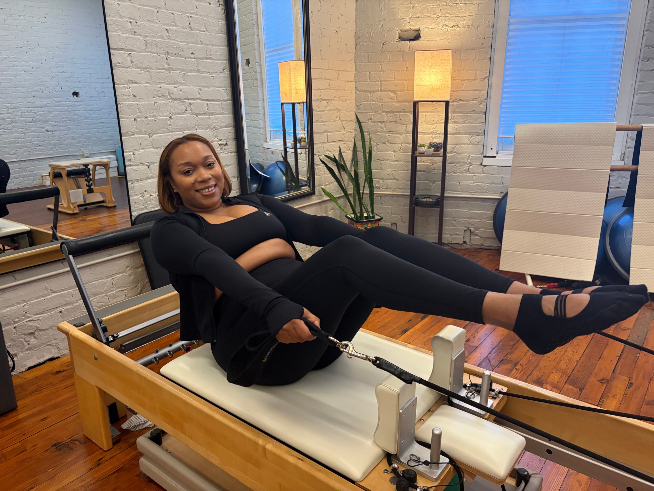 Woman lying on a medical or therapy bed in a room with large windows, plants, and modern decor.