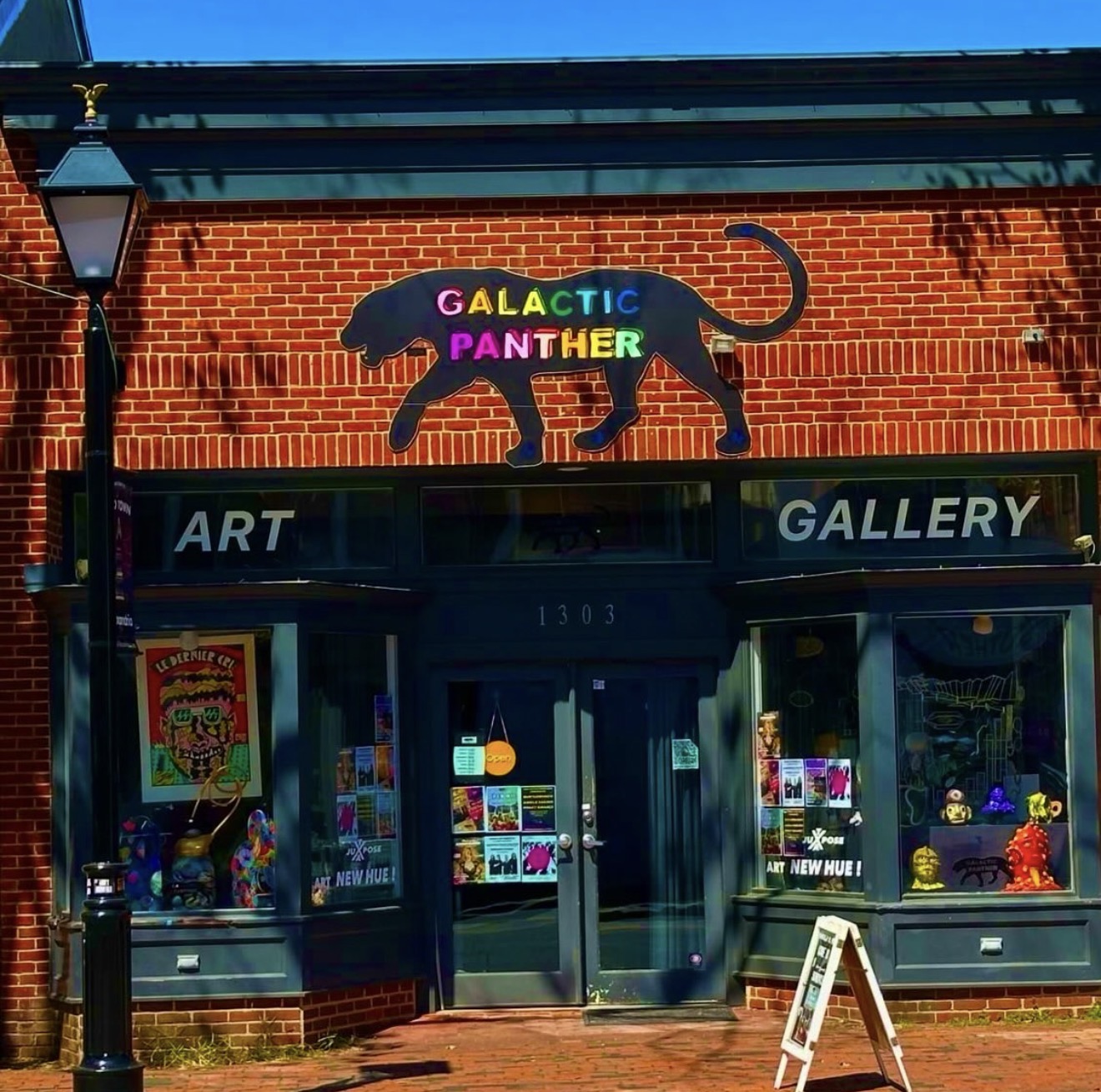 Brick art gallery storefront with a colorful sign of a panther and the words 'GALACTIC PANTHER' above the entrance.